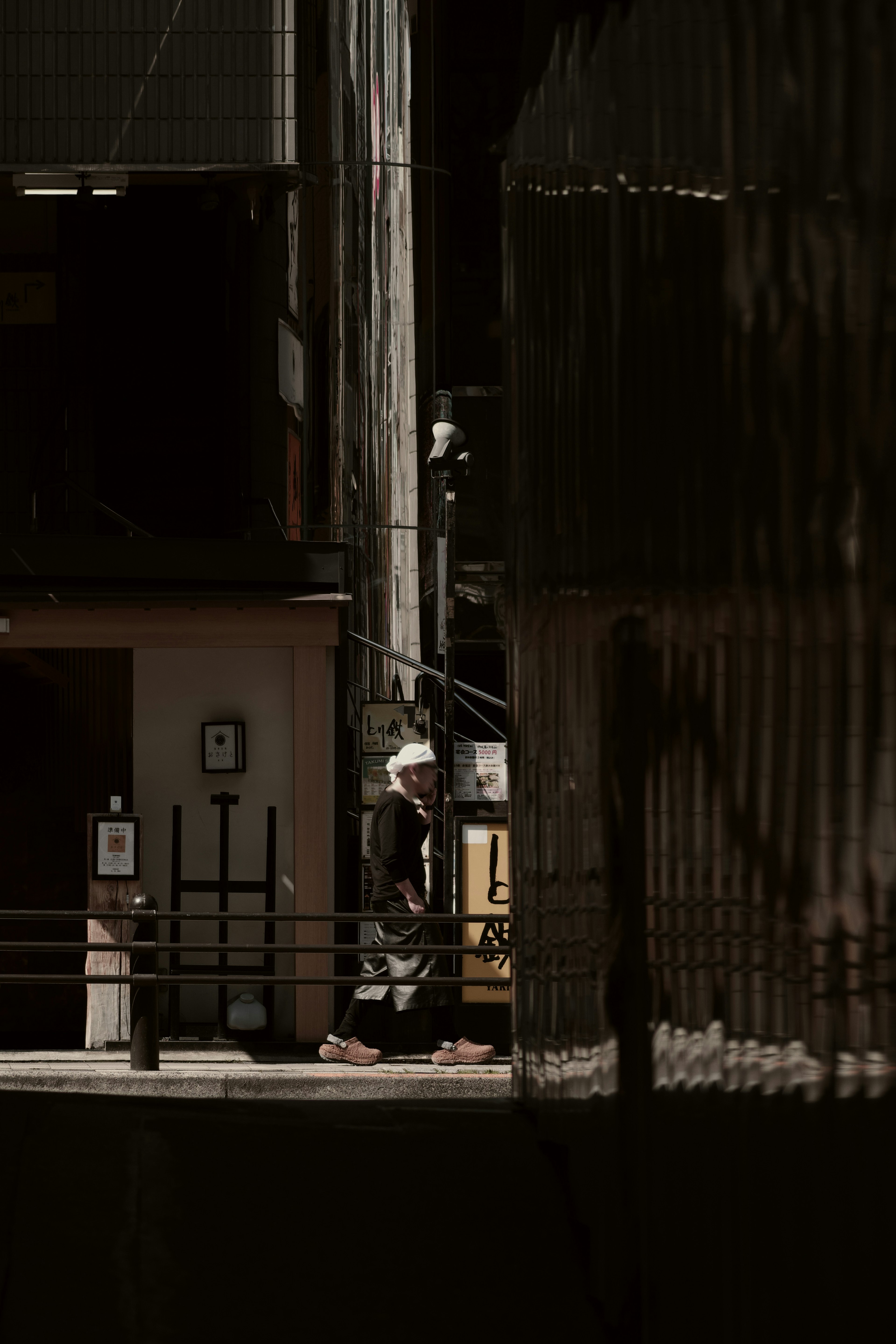 Person walking in a dimly lit alley with surrounding buildings