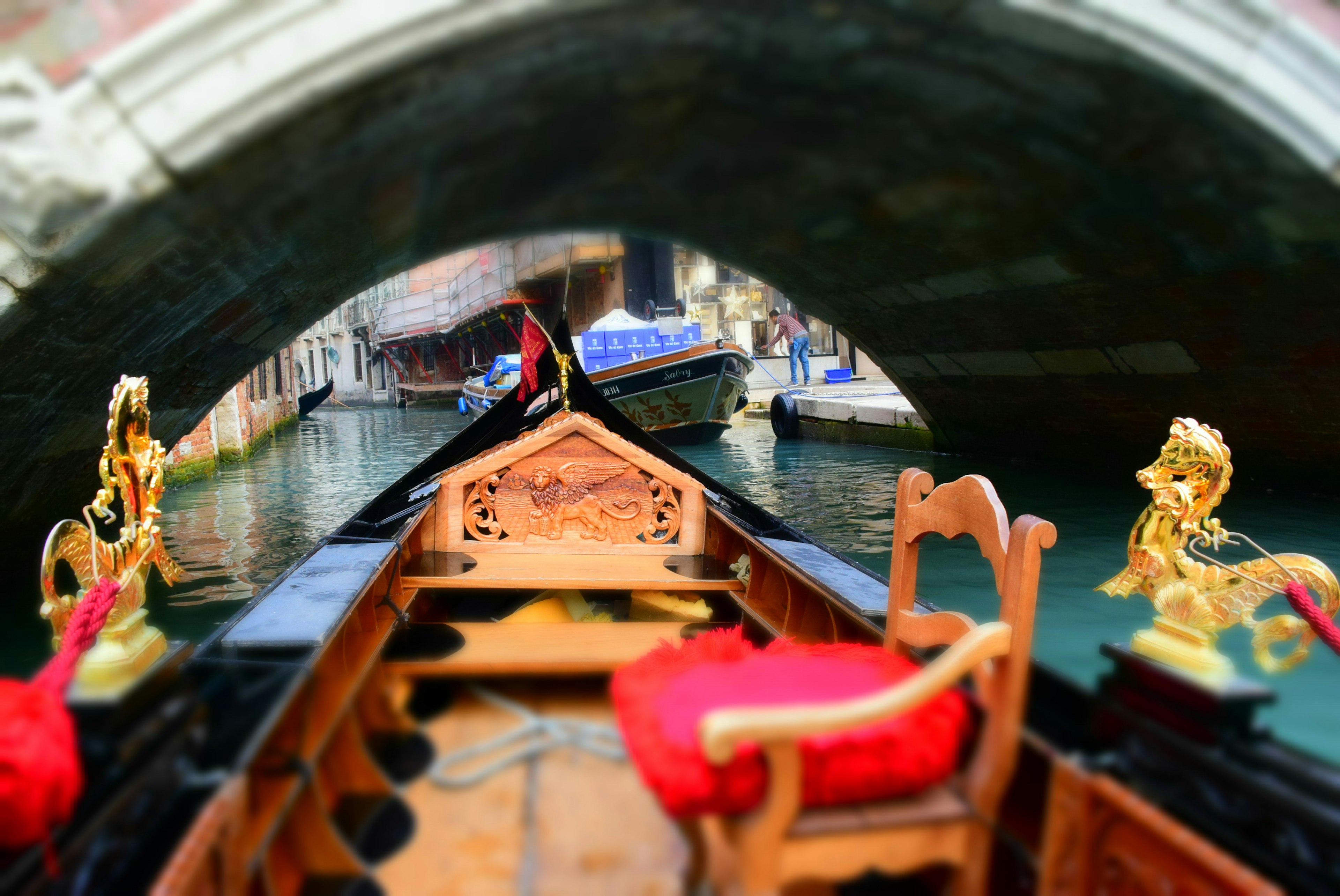 View of a gondola with ornate decorations under a beautiful arch bridge