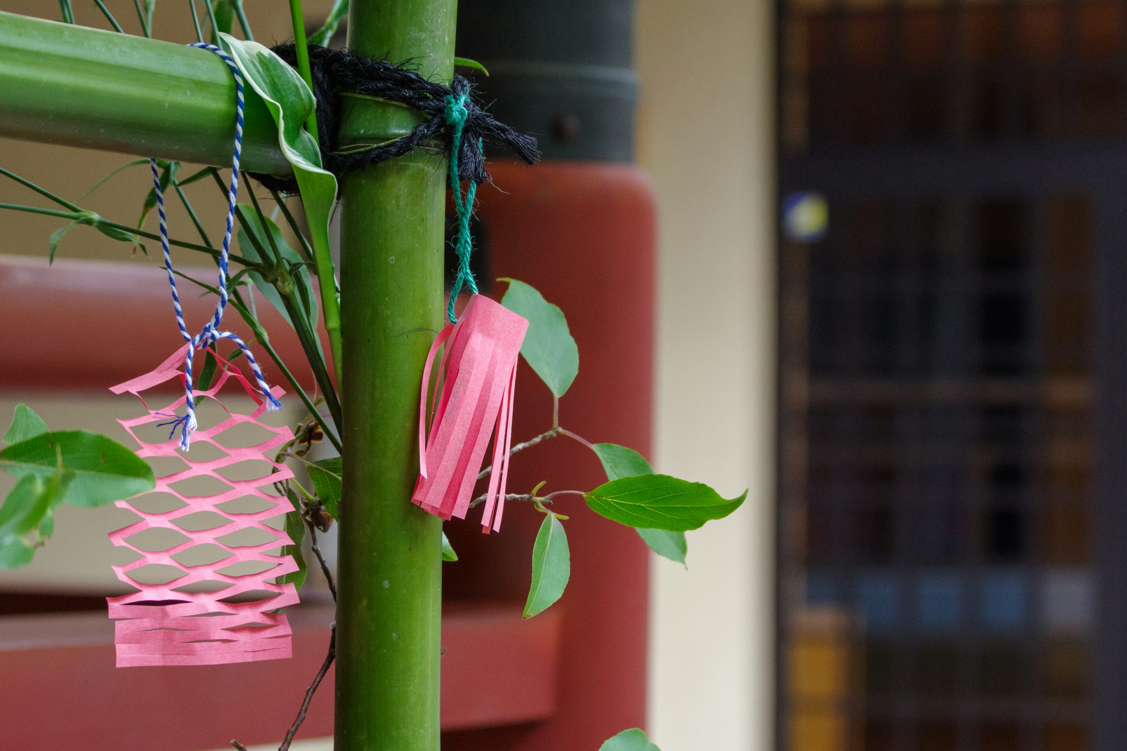 Un bambou vert avec des décorations roses et des feuilles attachées