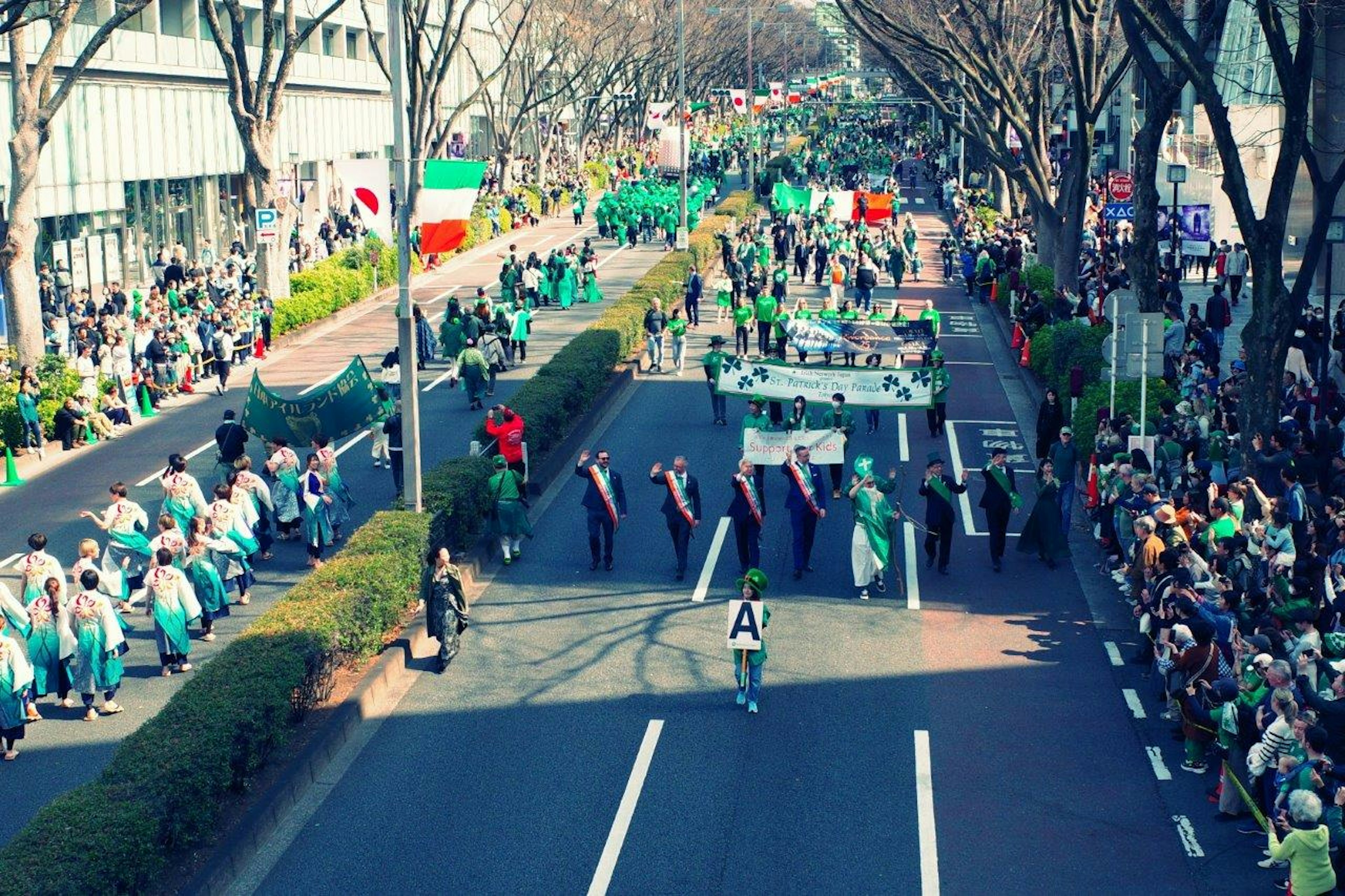 Participantes del desfile con trajes verdes marchando por la calle