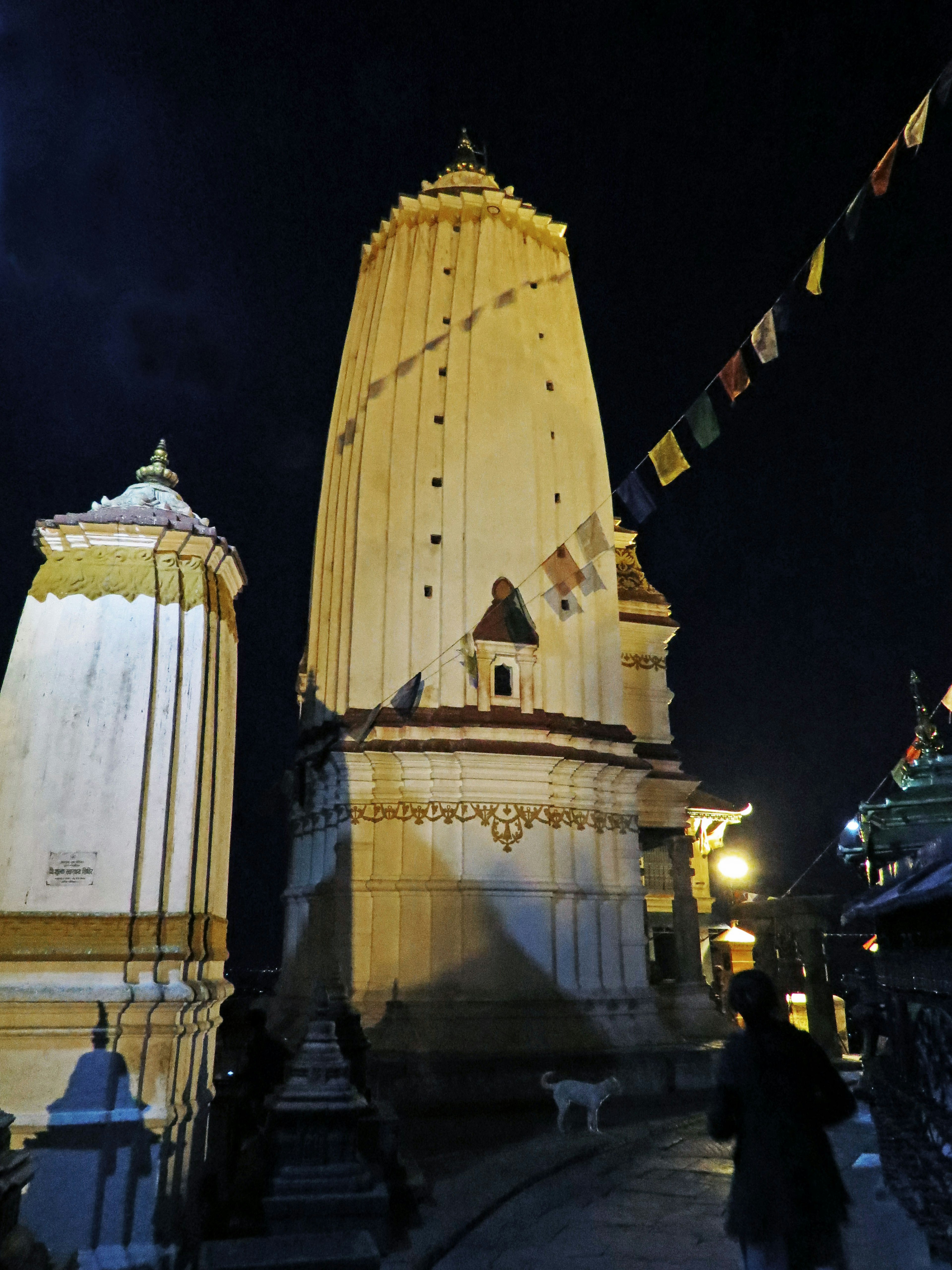 Vue nocturne d'une tour de temple avec des drapeaux de prière bouddhistes