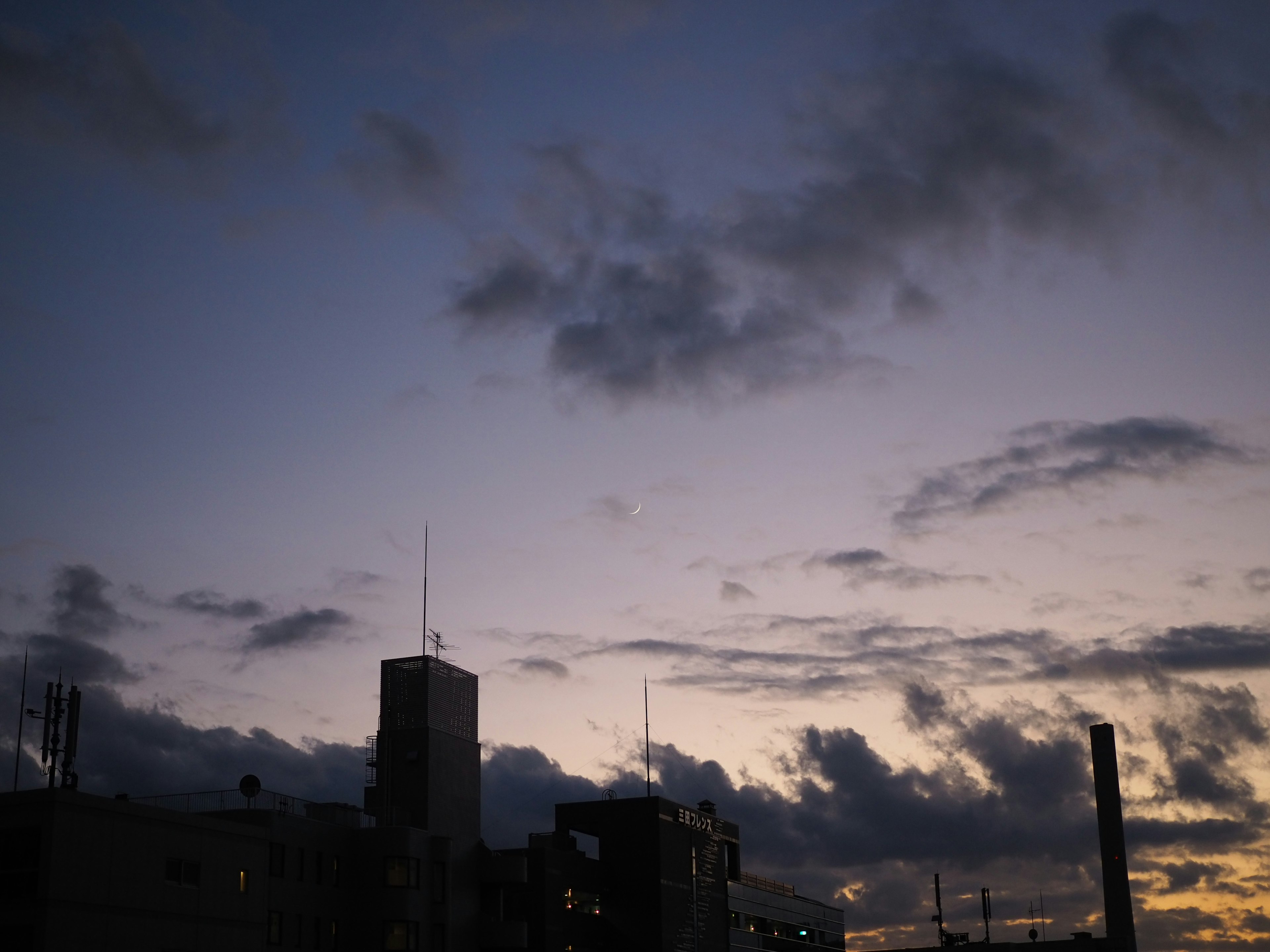 Silhouette di edifici contro un cielo crepuscolare con nuvole sparse