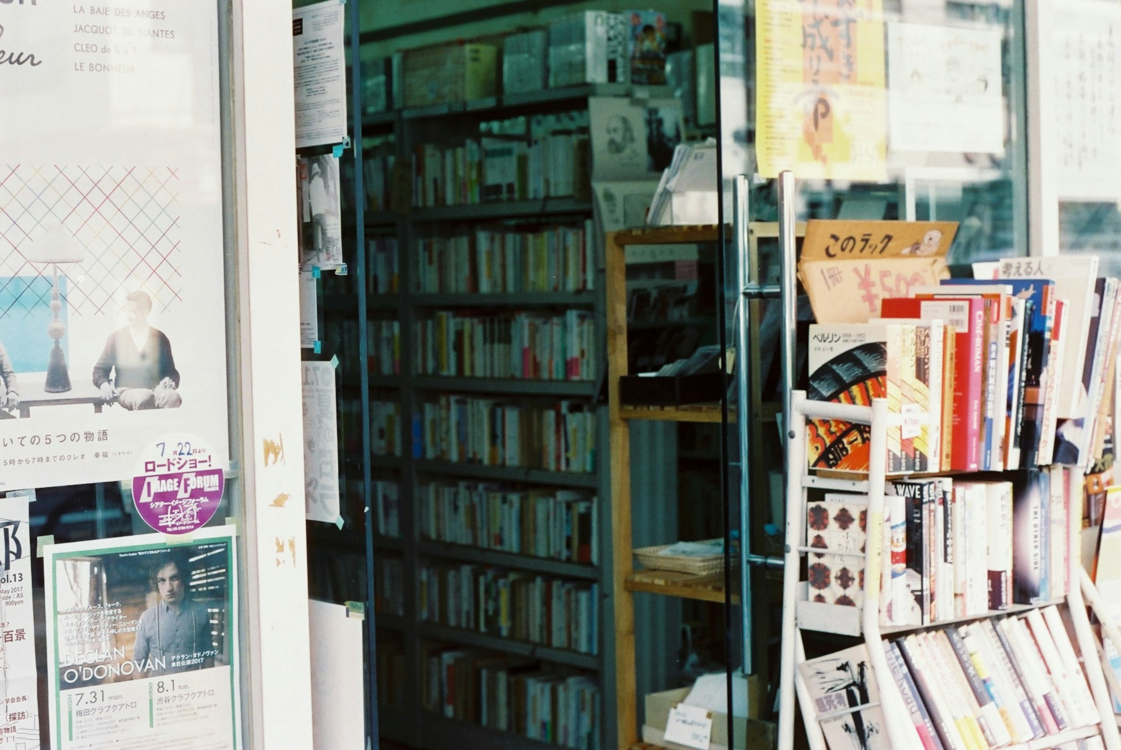 มุมมองภายนอกของร้านหนังสือที่มีชั้นวางหนังสือมองเห็นผ่านประตูกระจก