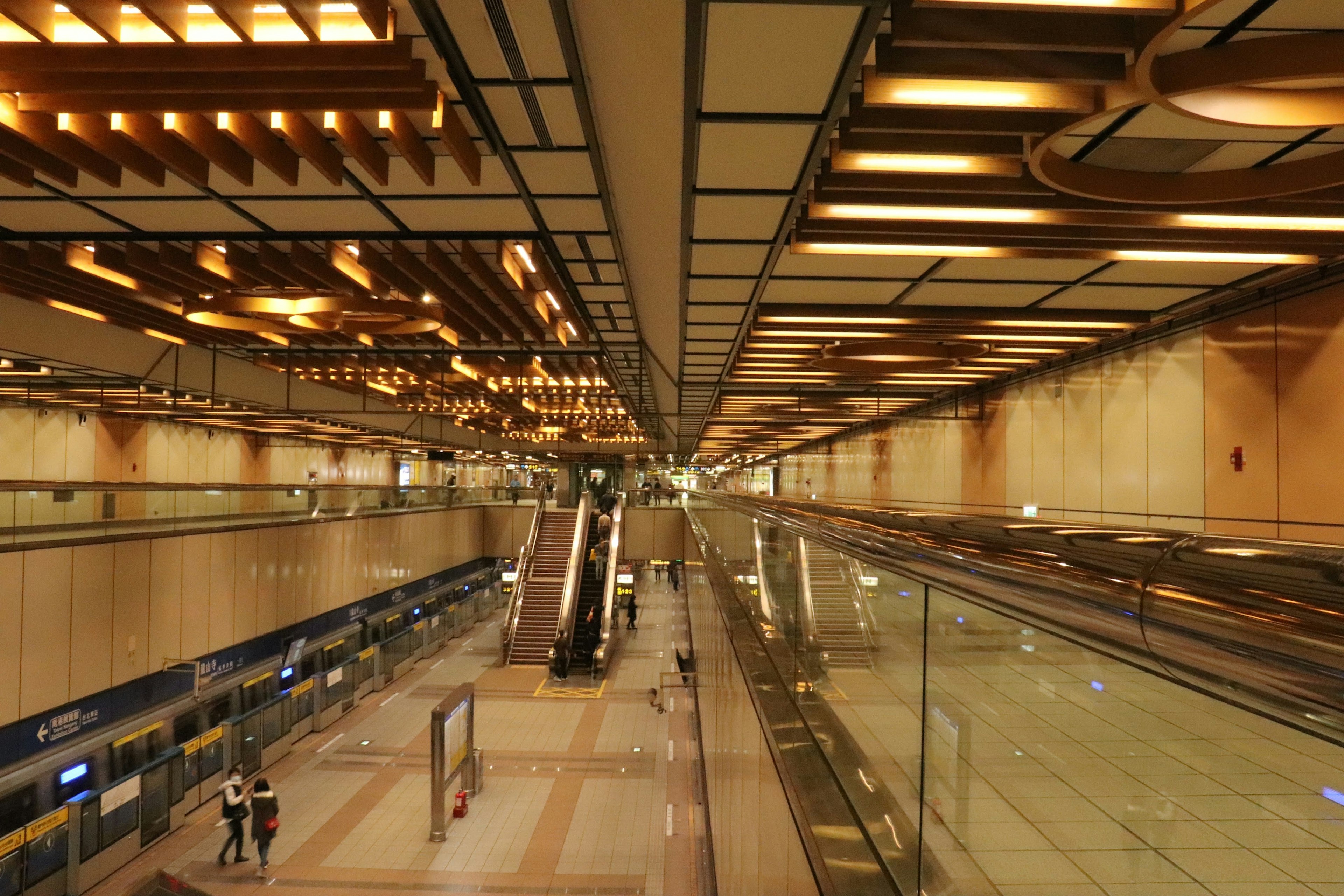 Modern interior of an airport featuring silver escalators and wooden decorations