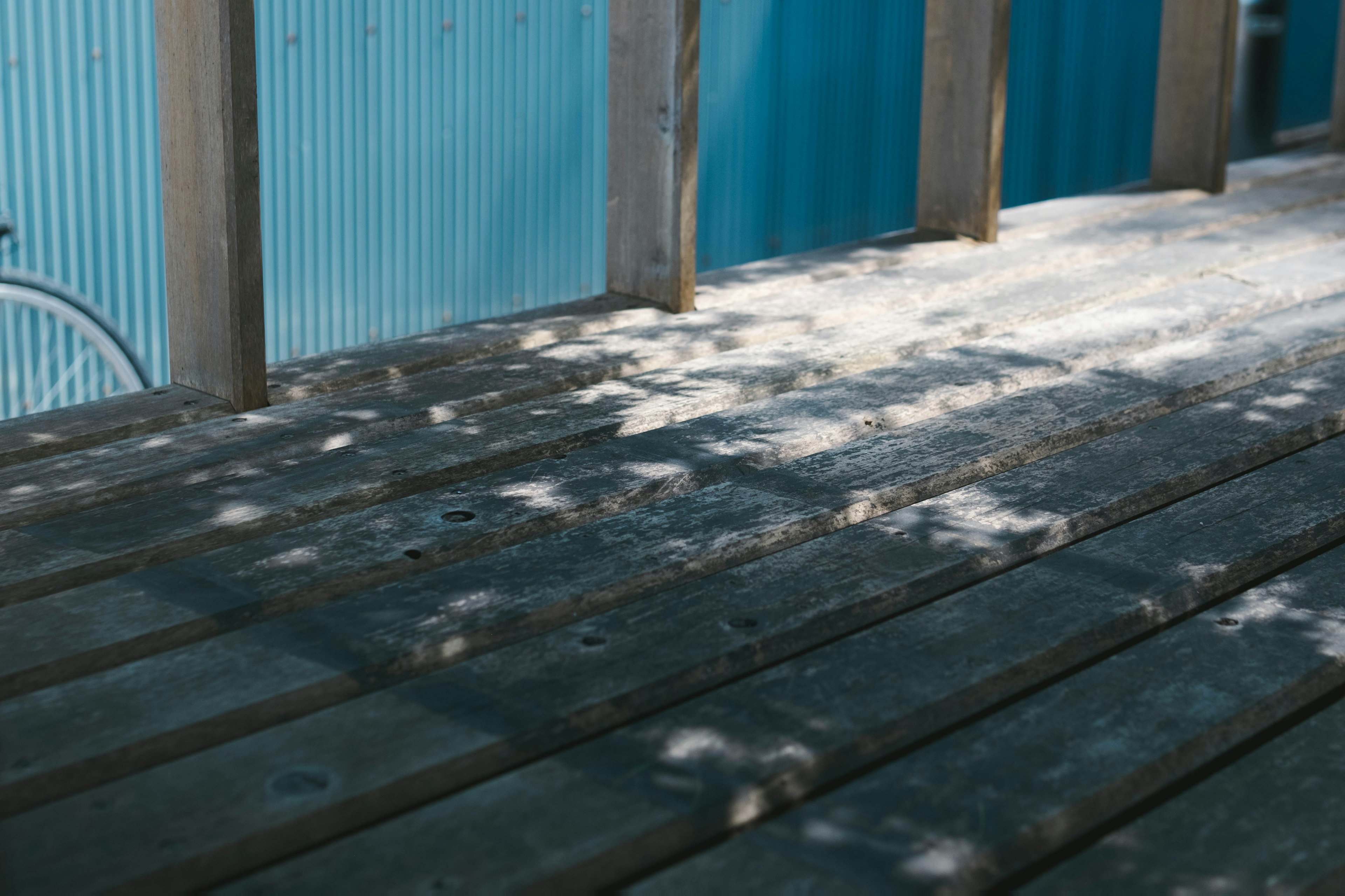 Terrasse en bois avec des ombres et un mur bleu en arrière-plan