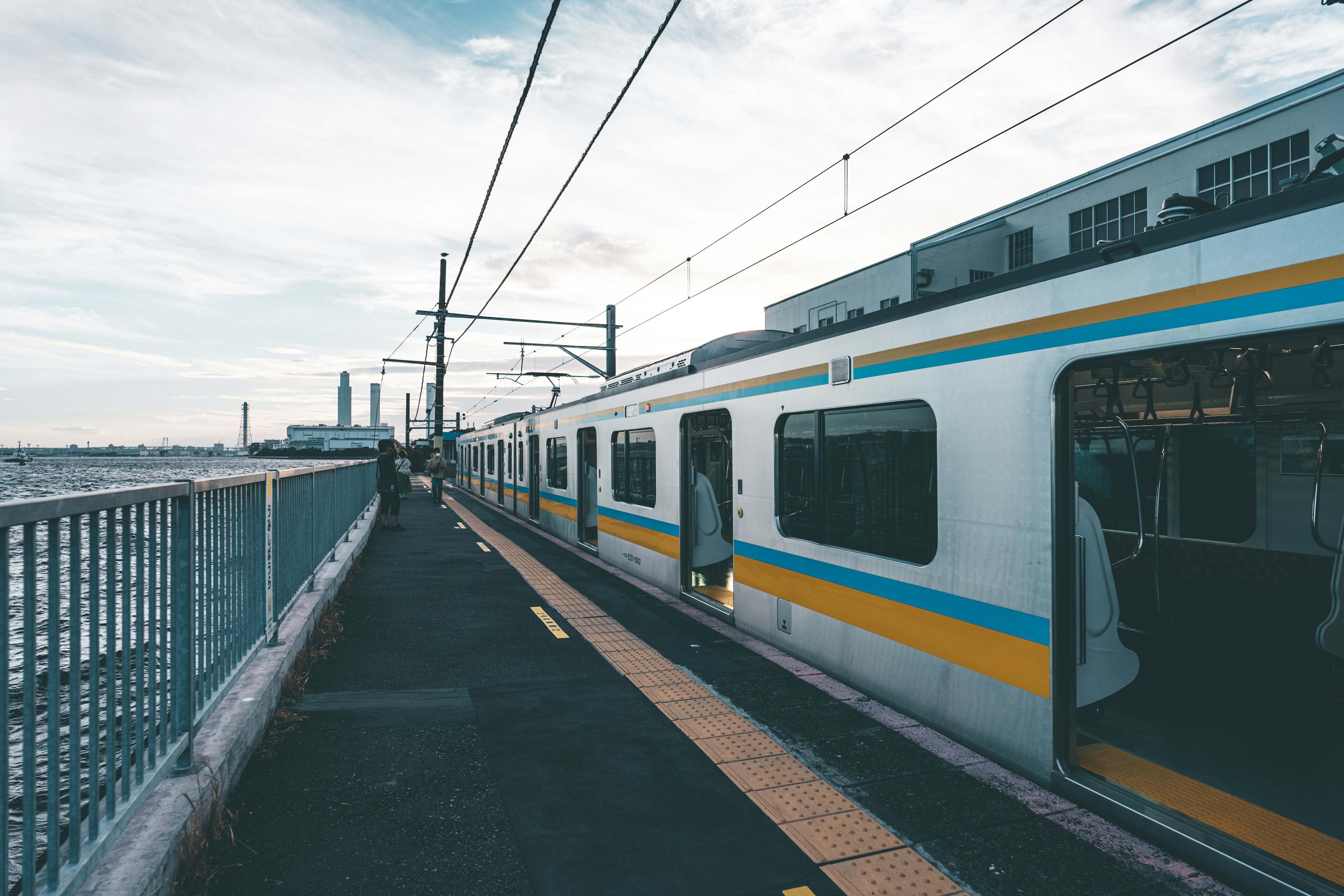 Train stopped at a seaside station with a cloudy sky