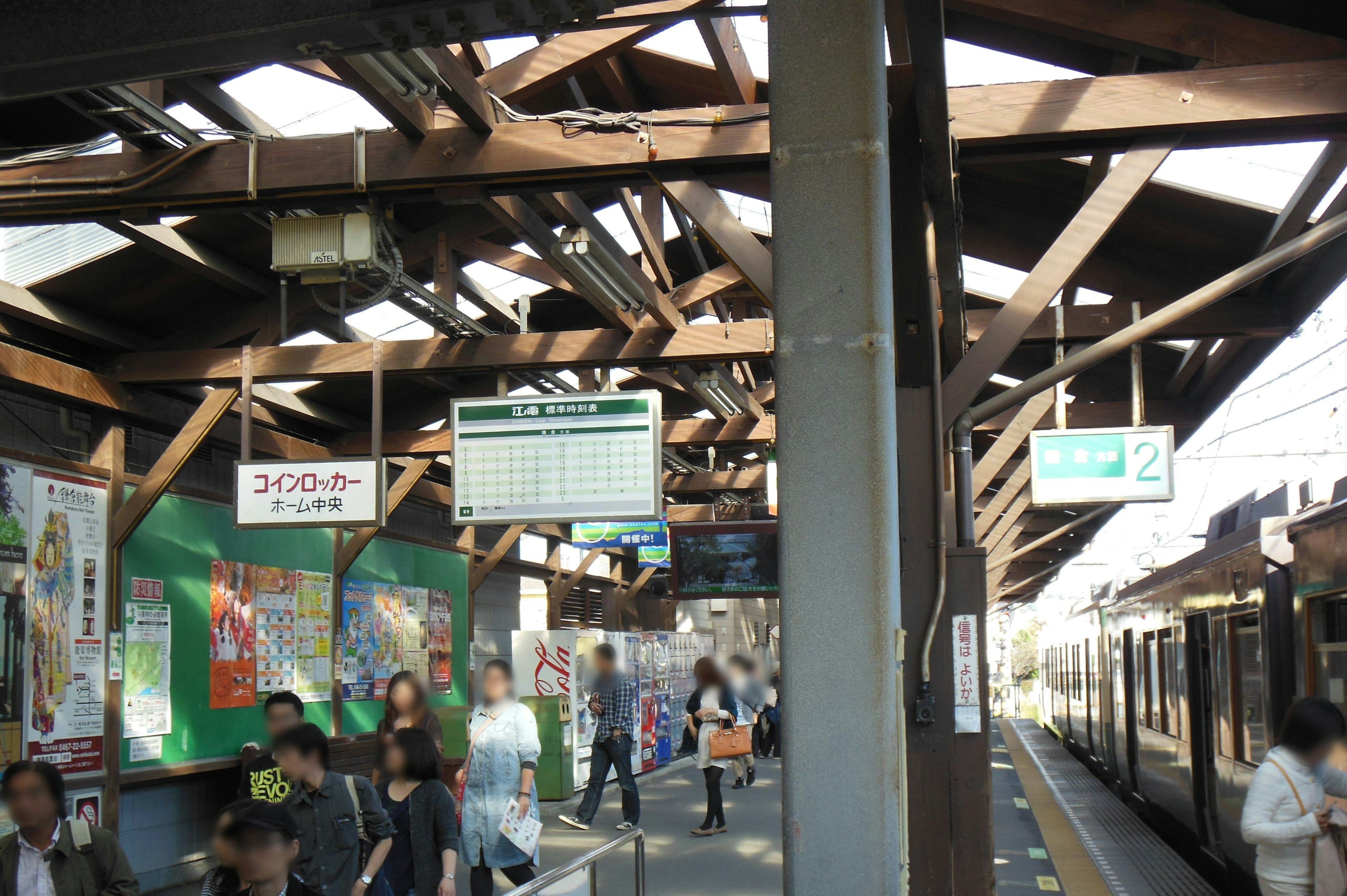 駅のホームにいる人々と木造の屋根が特徴の風景