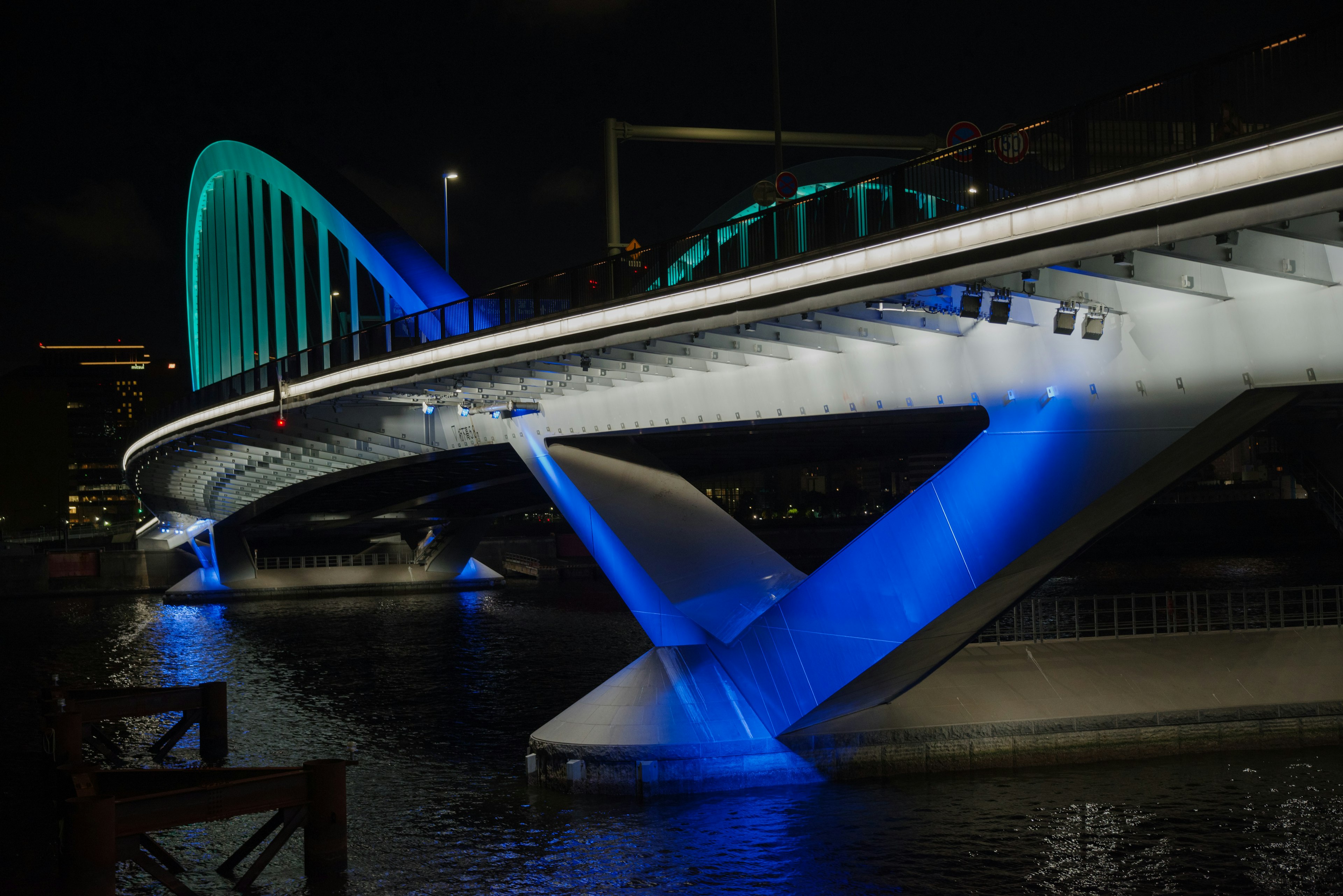 Modern bridge illuminated in blue and green lights at night