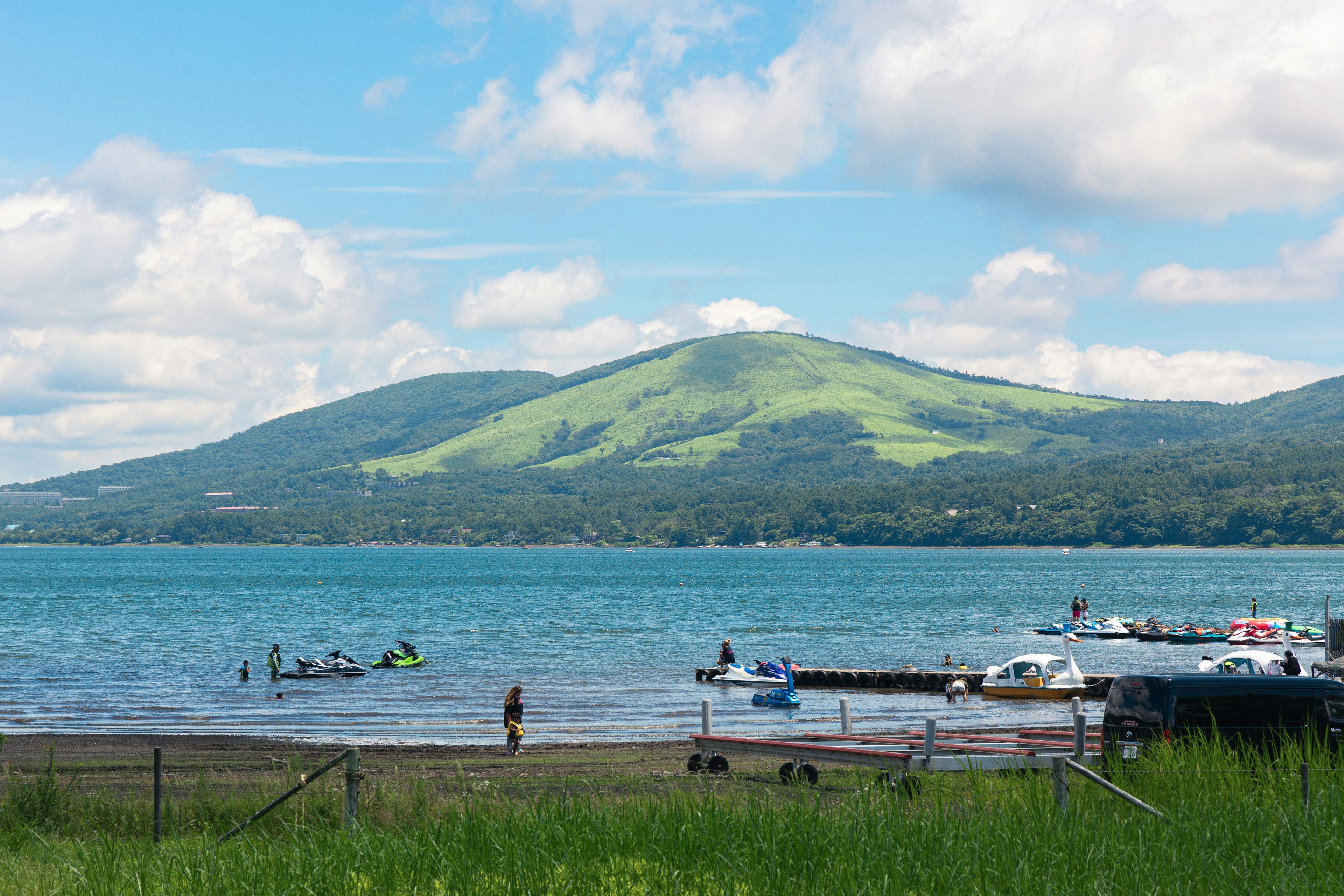 Malersicher Blick auf einen See mit grünen Hügeln und Menschen beim Bootfahren