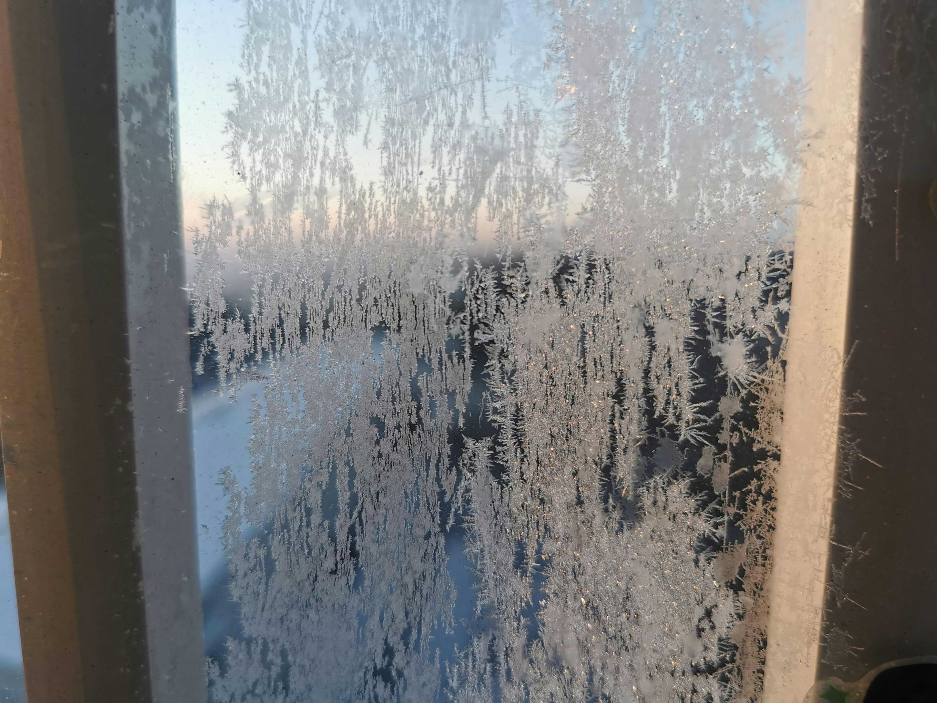 Eingefrorene Fensteransicht mit komplexen Eiskristallen auf dem Glas