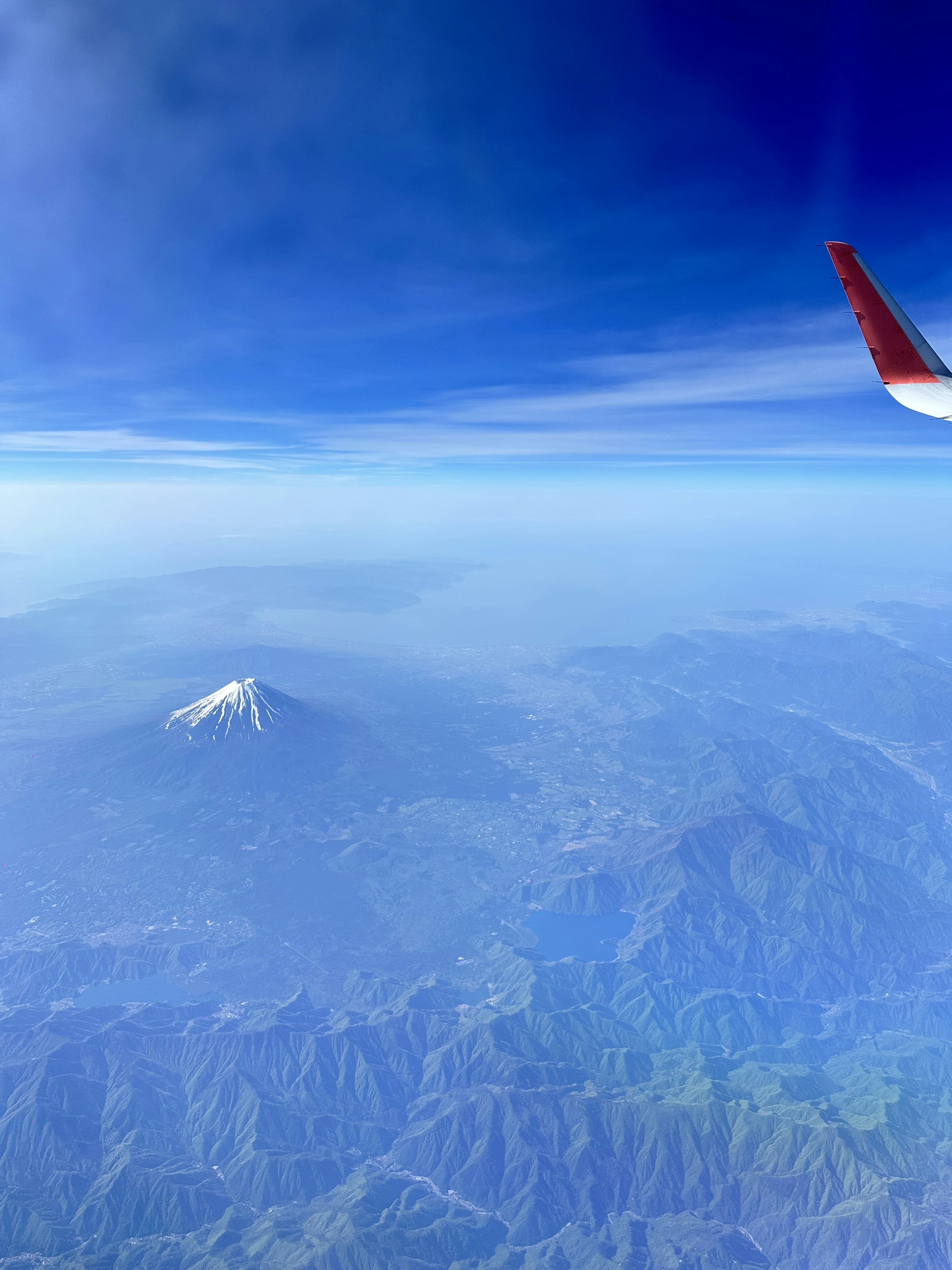 Monte innevato visto da un finestrino dell'aereo con cielo blu