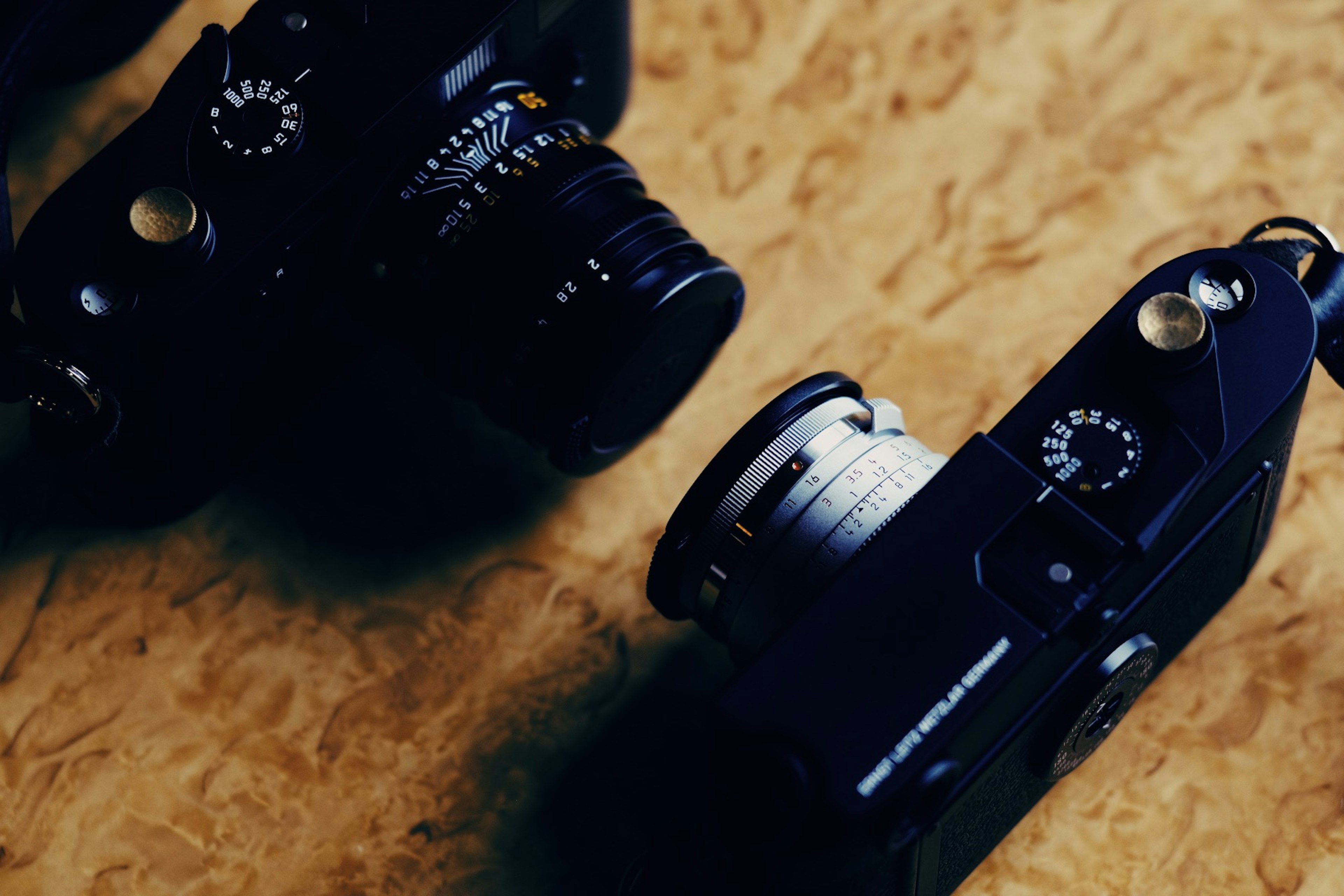 Two cameras placed on a wooden table