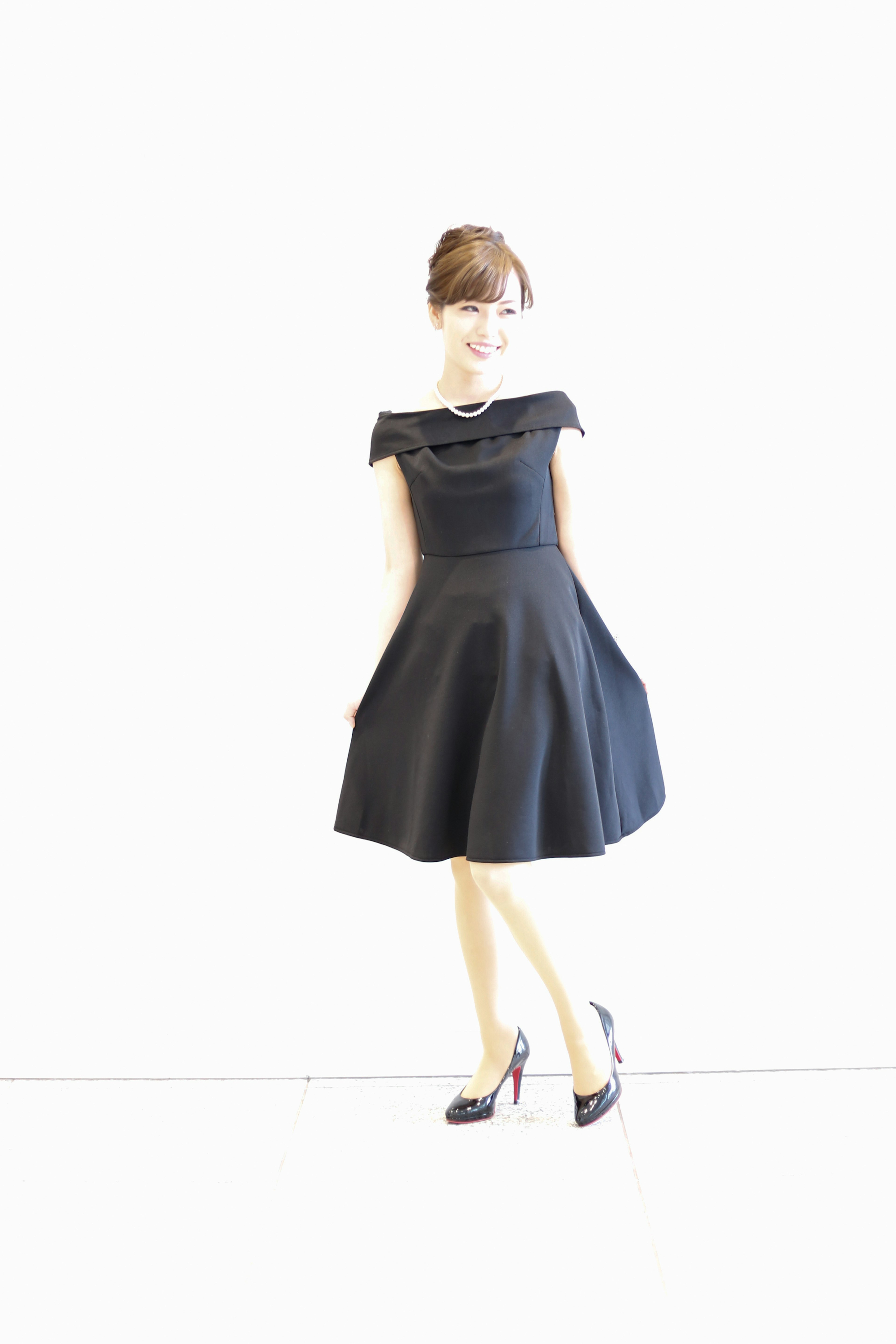 A woman in a black dress standing in front of a white background