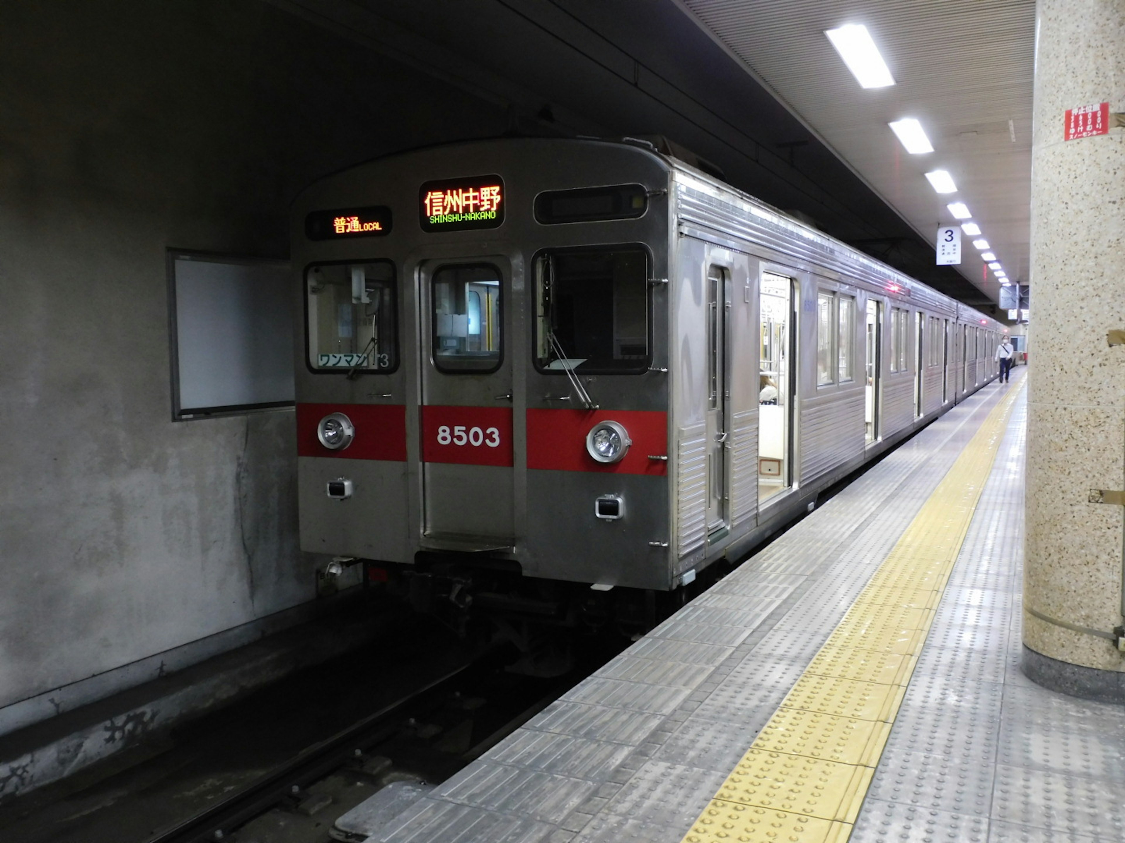 Silver subway train at a station with yellow tiled platform