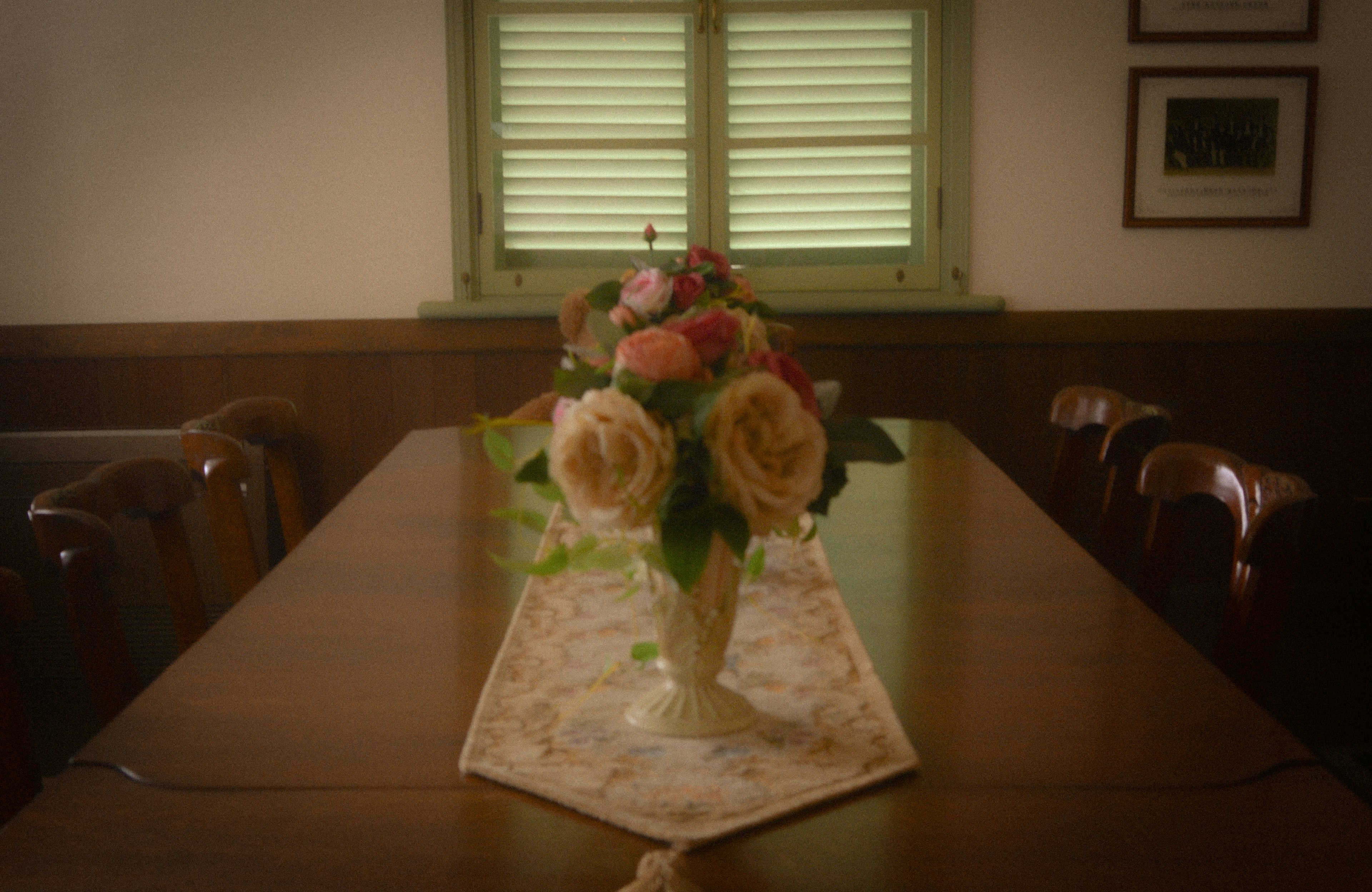 Interior of a quiet room featuring a vase of roses on a table with a decorative table runner