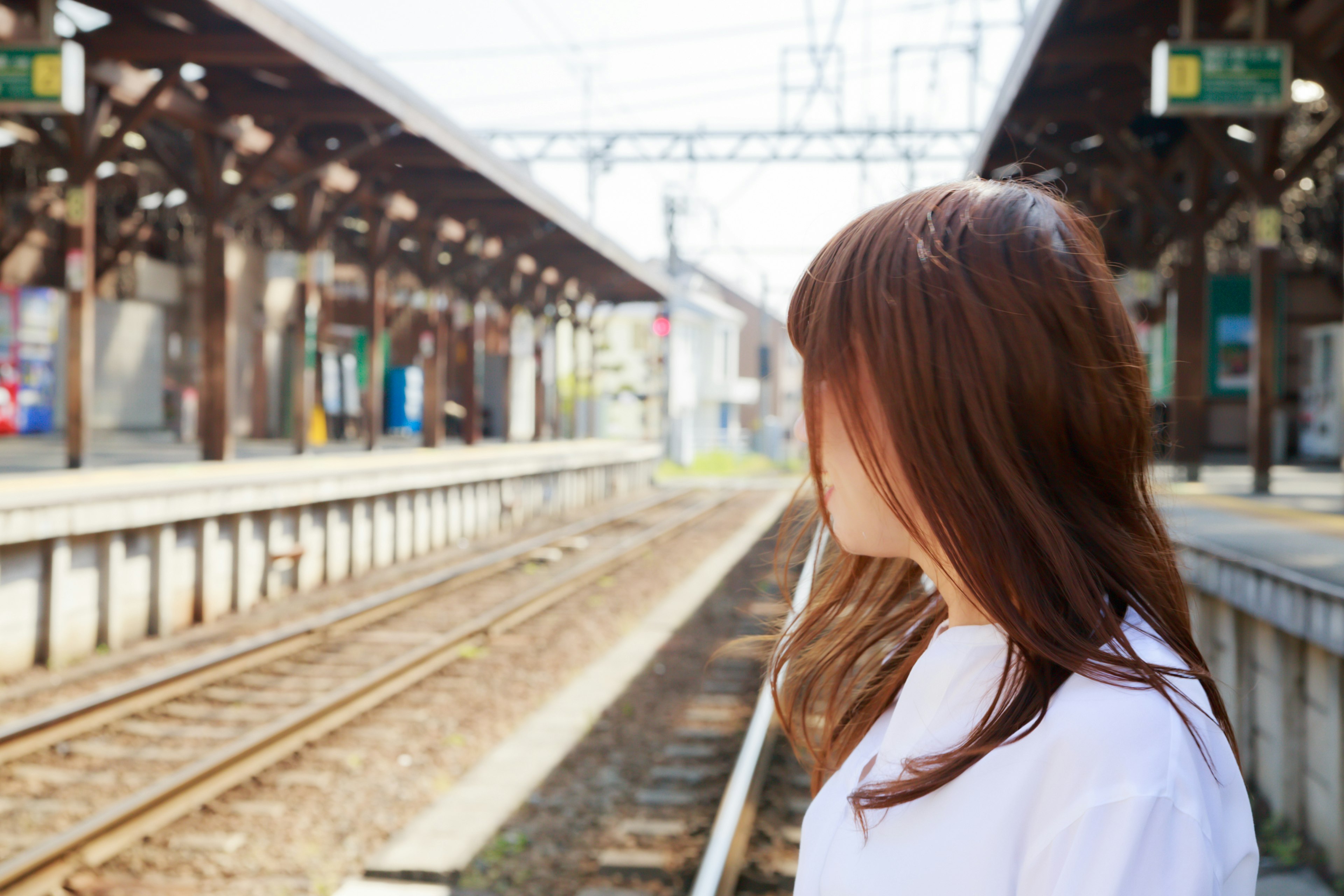 Seorang wanita menunggu di platform kereta dengan punggung menghadap