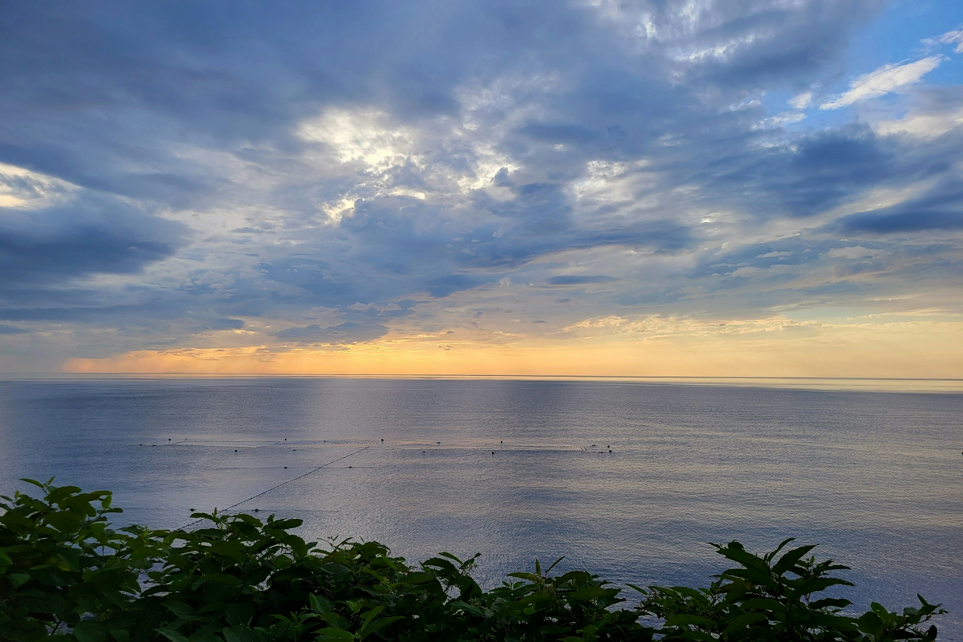 Pemandangan laut yang tenang dengan langit biru nuansa matahari terbenam yang indah