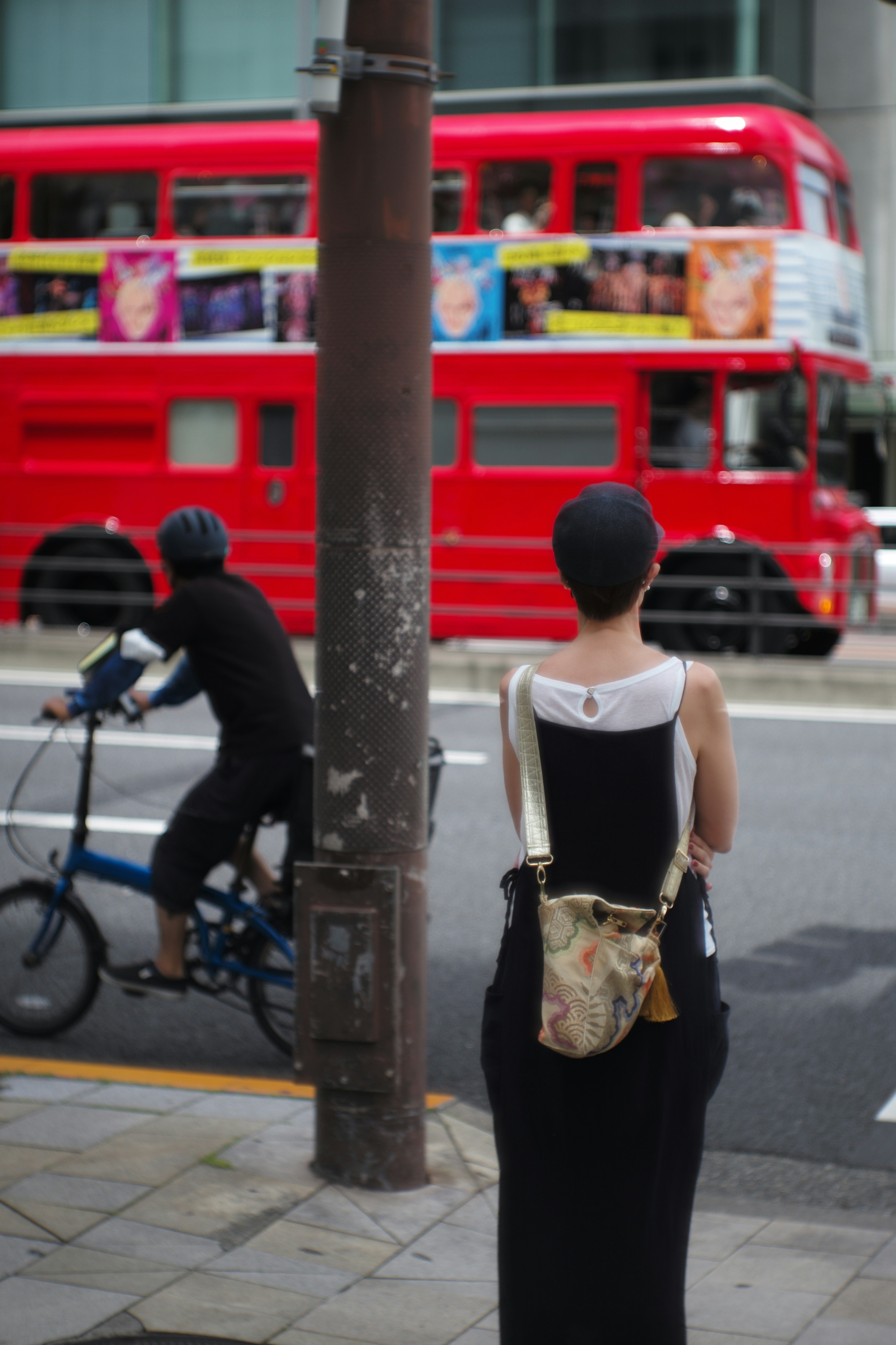 赤い二階建てバスと自転車に乗る人を背景に立つ女性