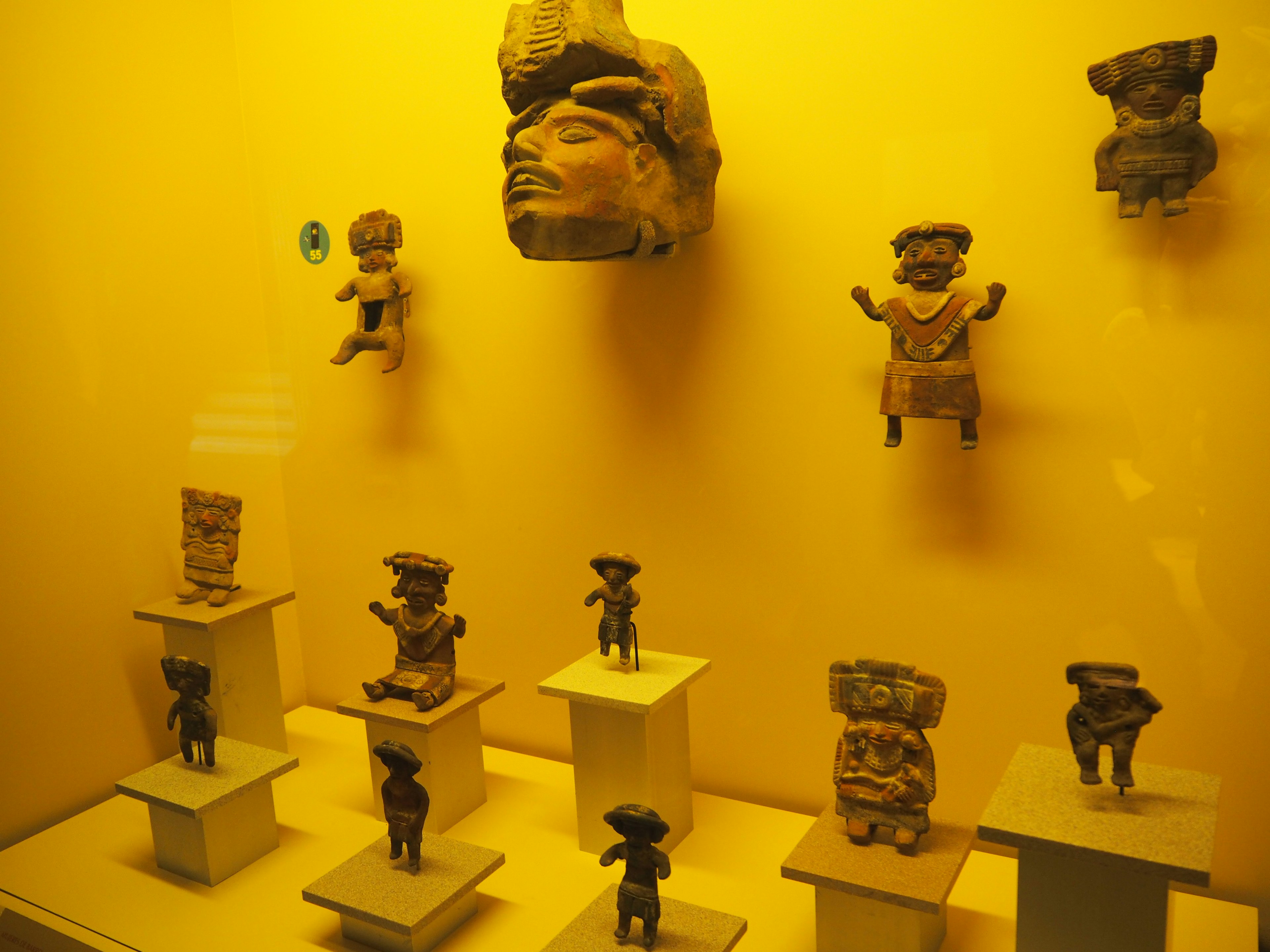 Ancient ceramic sculptures displayed against a yellow background