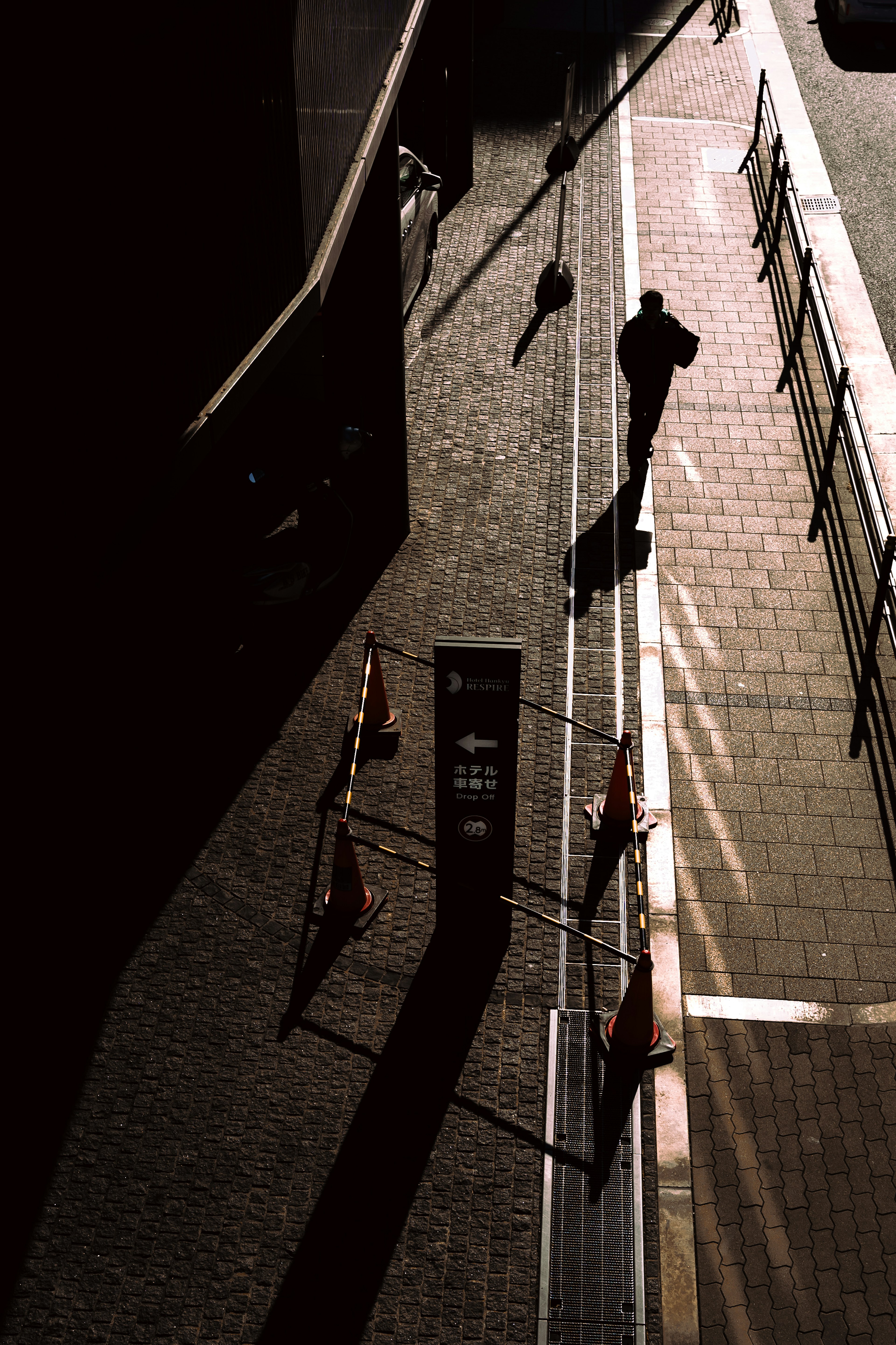 Silhouette d'une personne marchant dans l'ombre sur une rue pavée