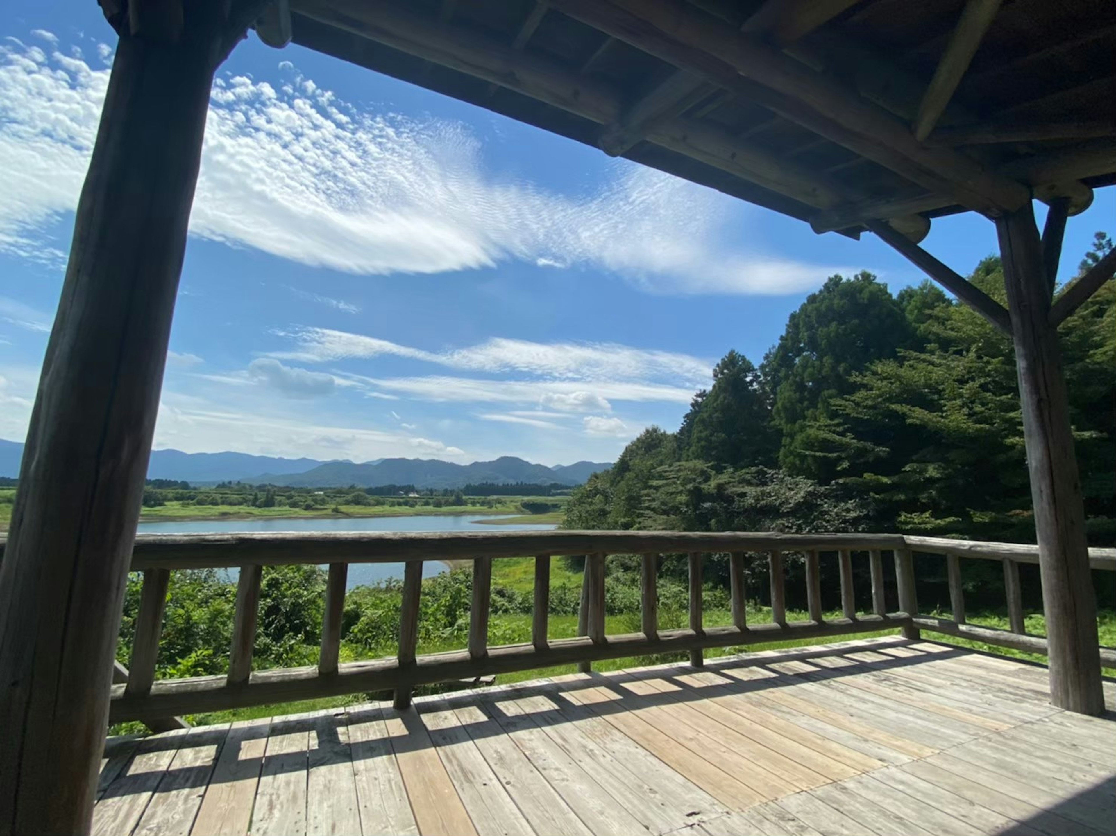 Scenic view from a wooden deck featuring blue sky and green landscape