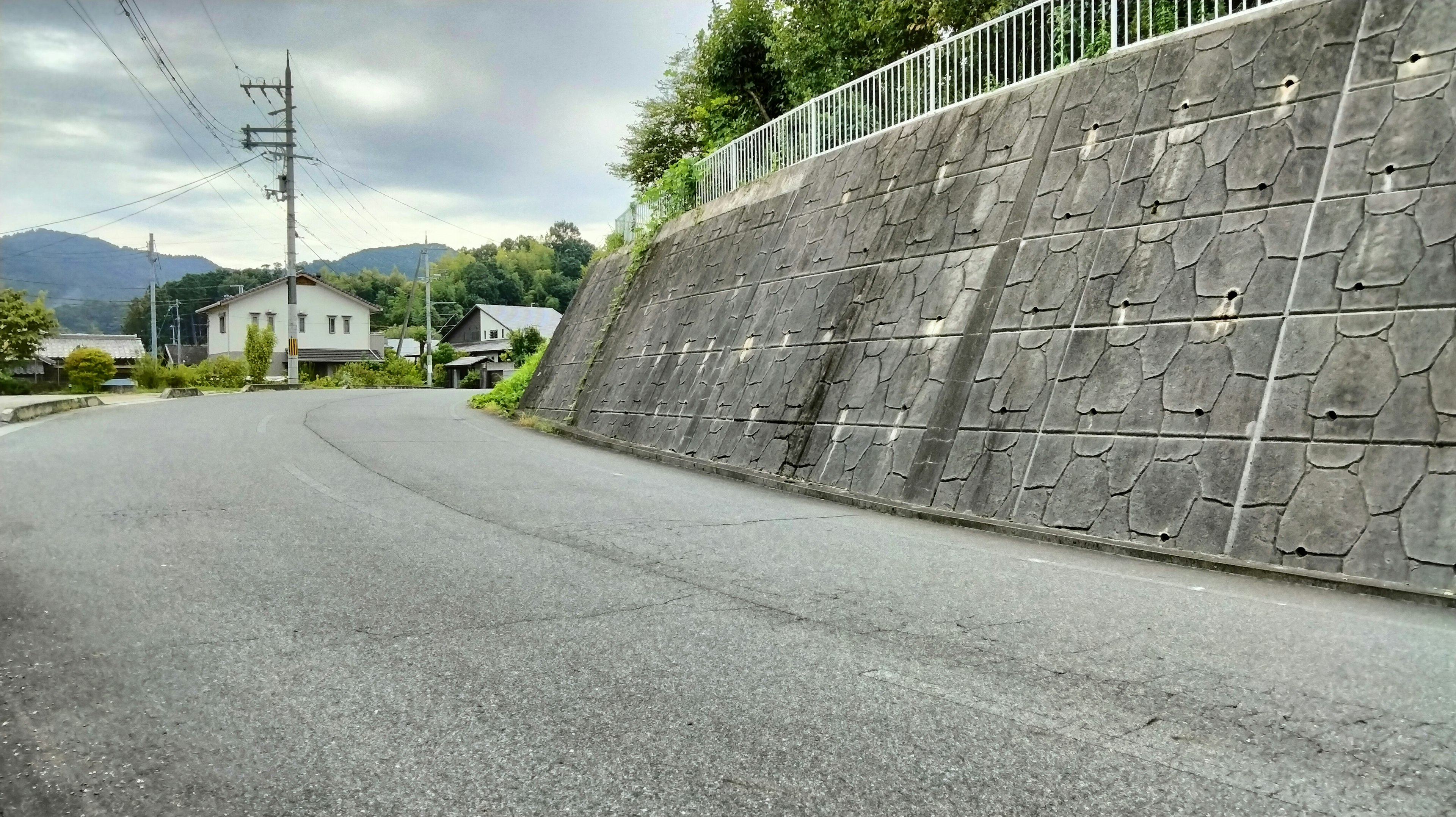 曲がり角のある道路とコンクリートの壁が見える風景