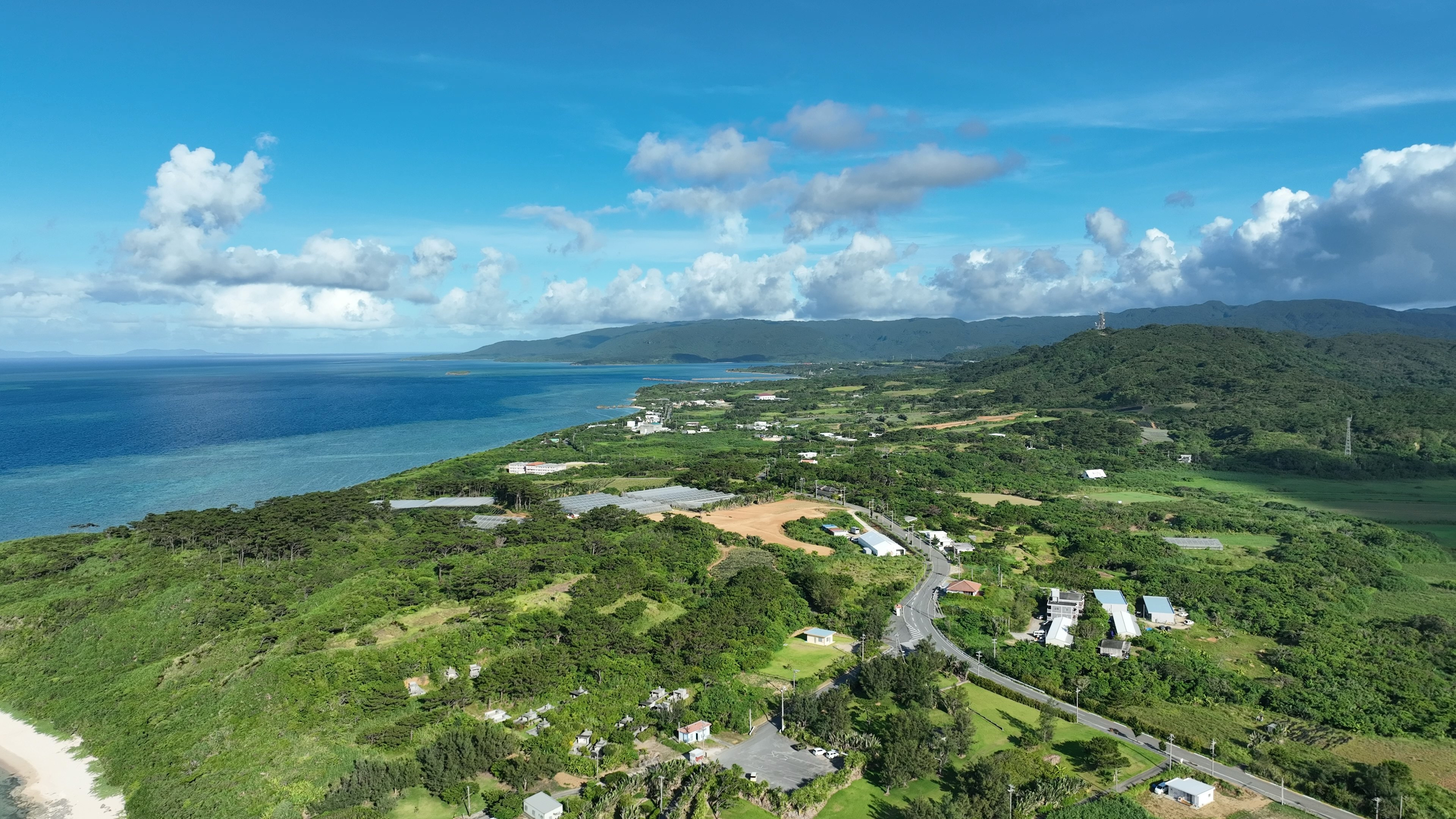 Luftaufnahme einer grünen Landschaft mit blauem Ozean und Wolken