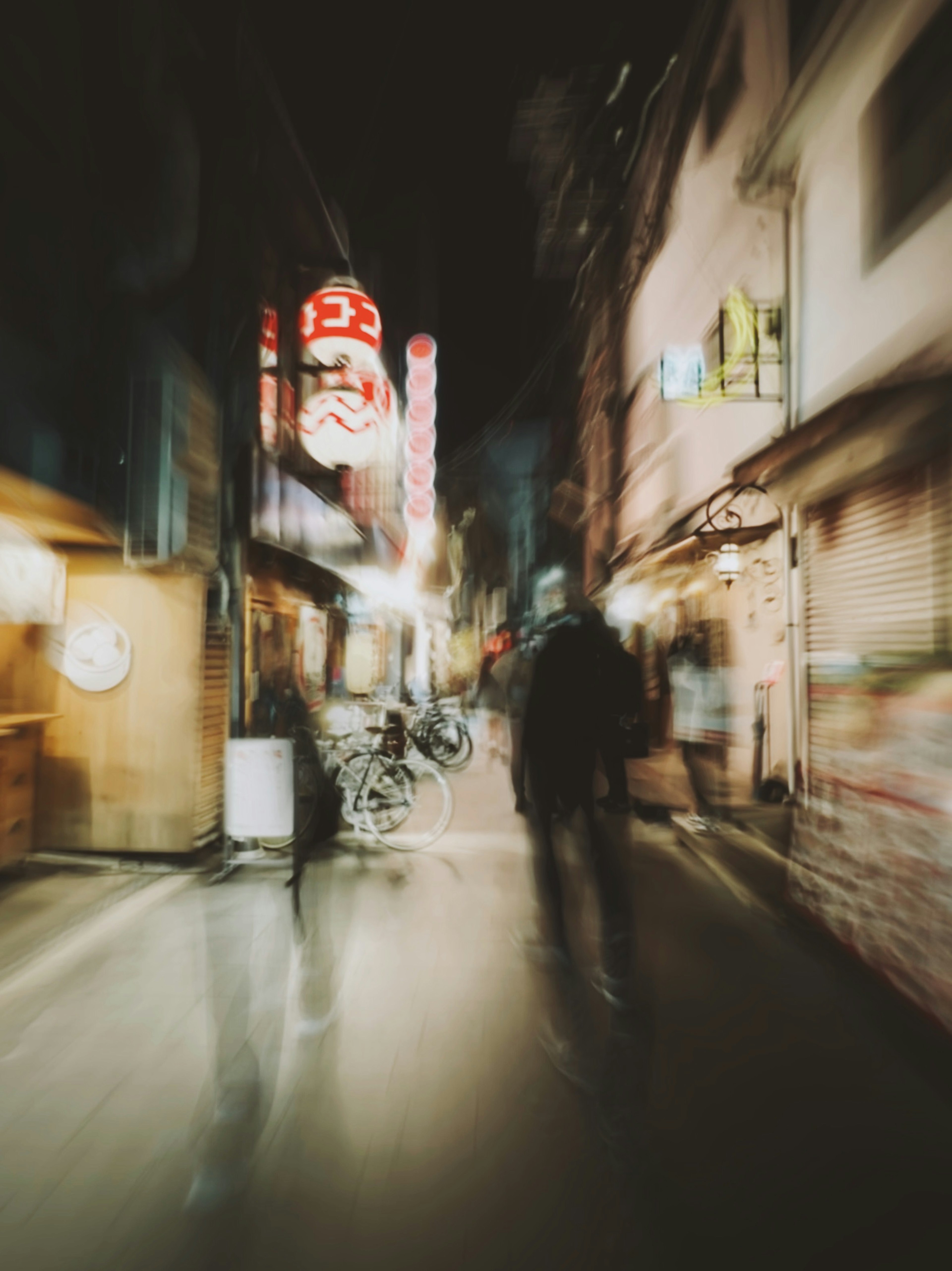 夜の街並みを歩く人々とぼやけた看板のある通り