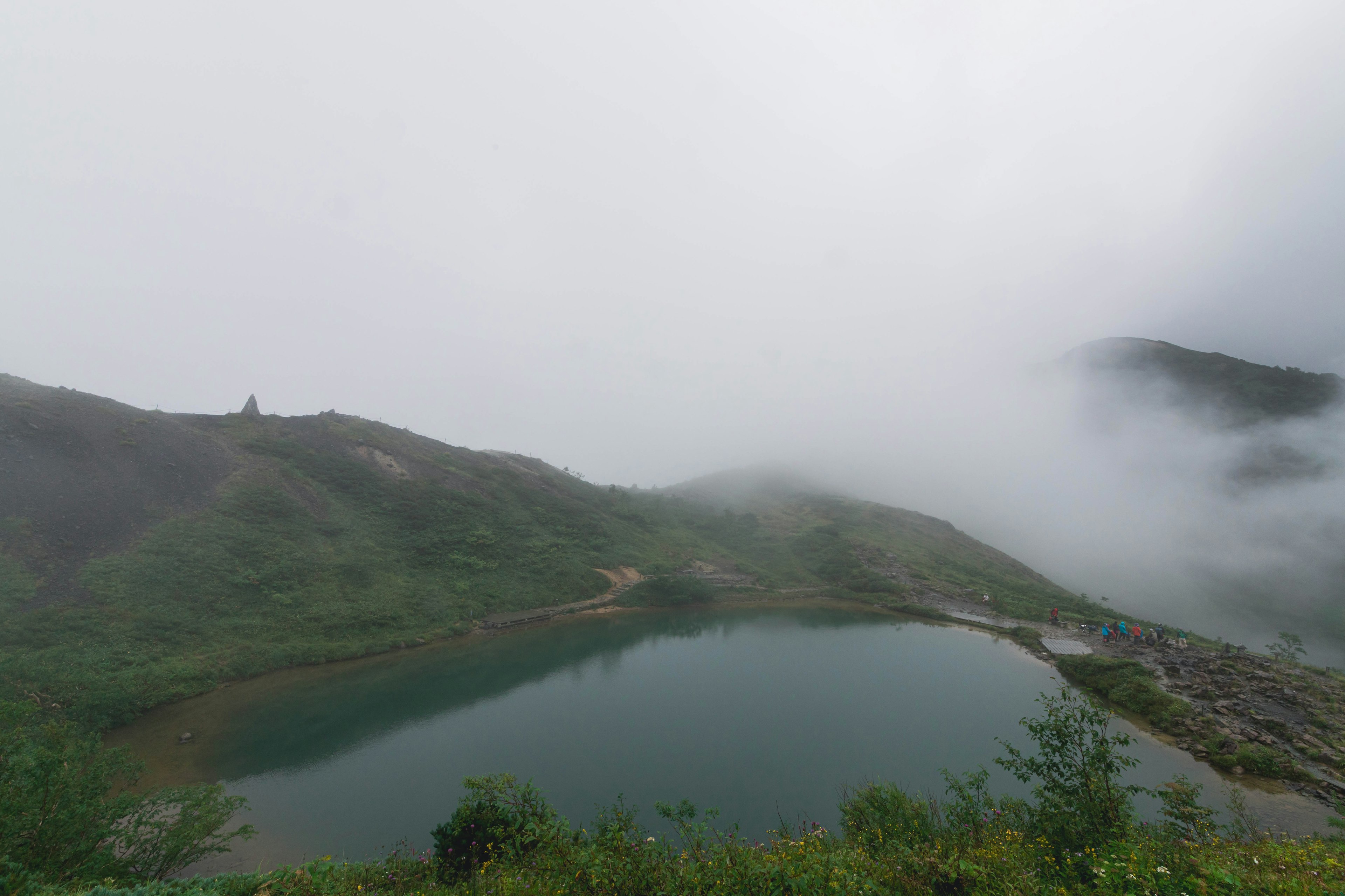 Gunung berkabut mengelilingi danau tenang