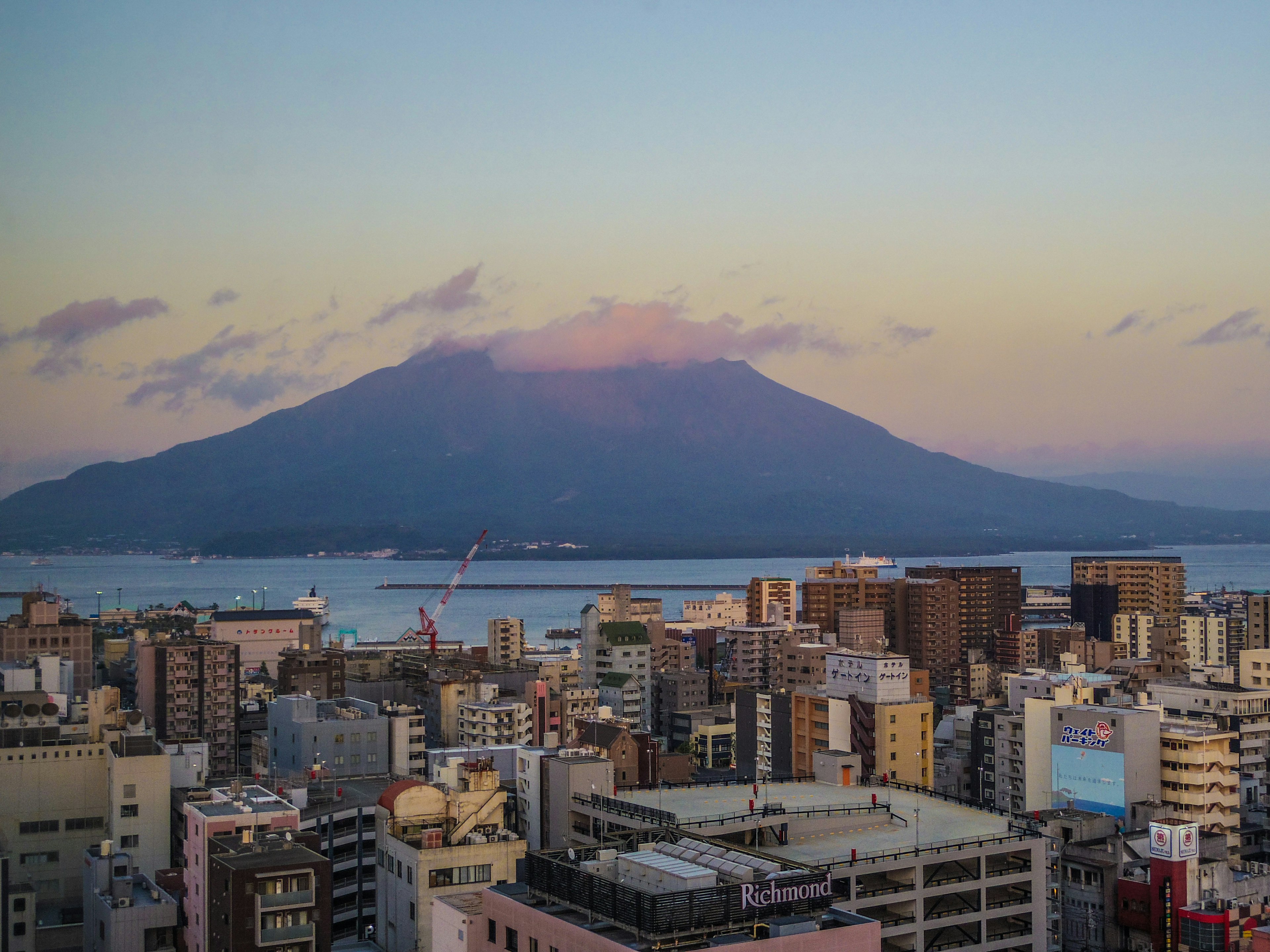 Stadtansicht mit dem Vulkan Sakurajima bei Sonnenuntergang