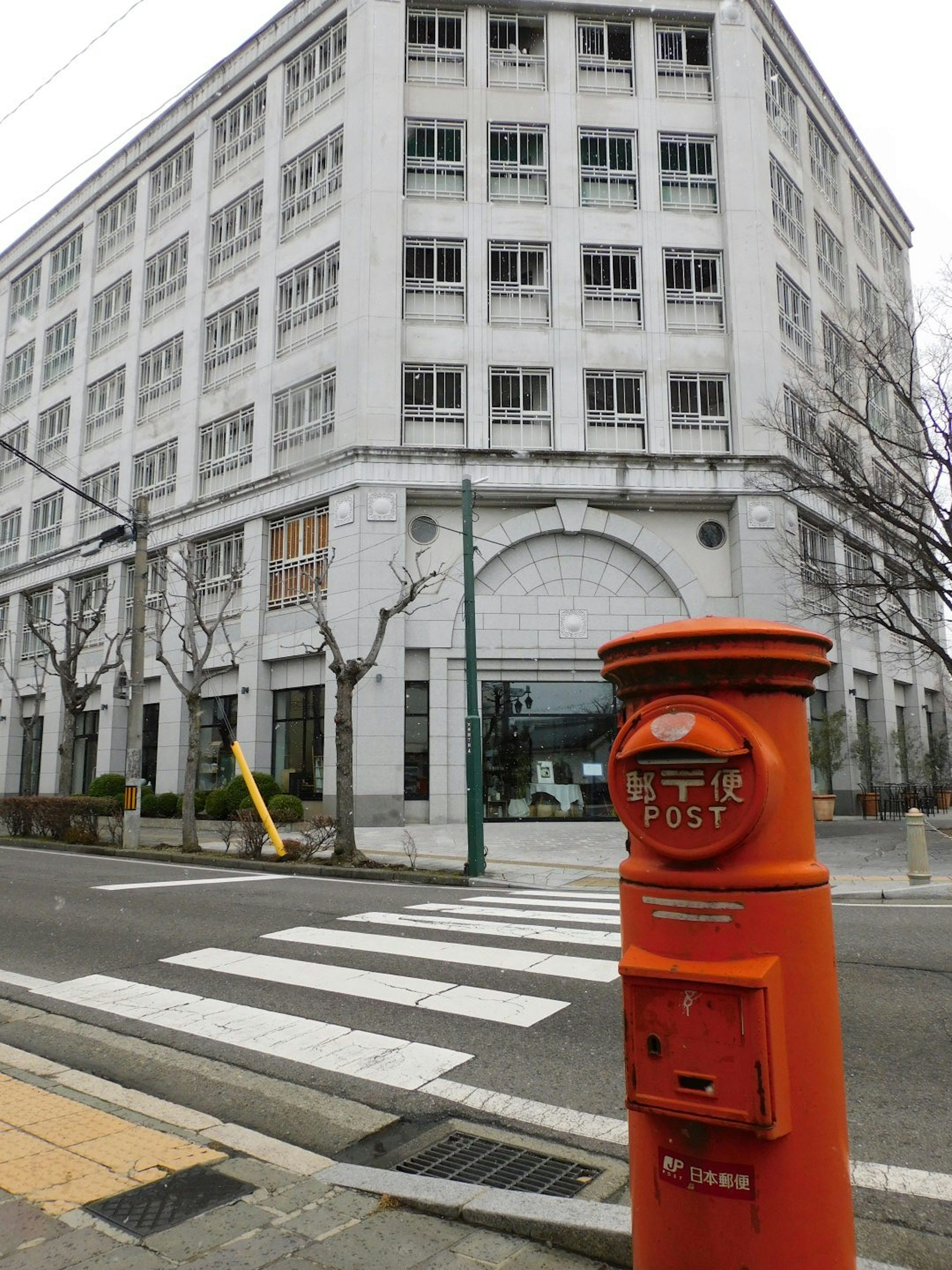 Boîte aux lettres orange à côté d'un bâtiment moderne au coin de la rue