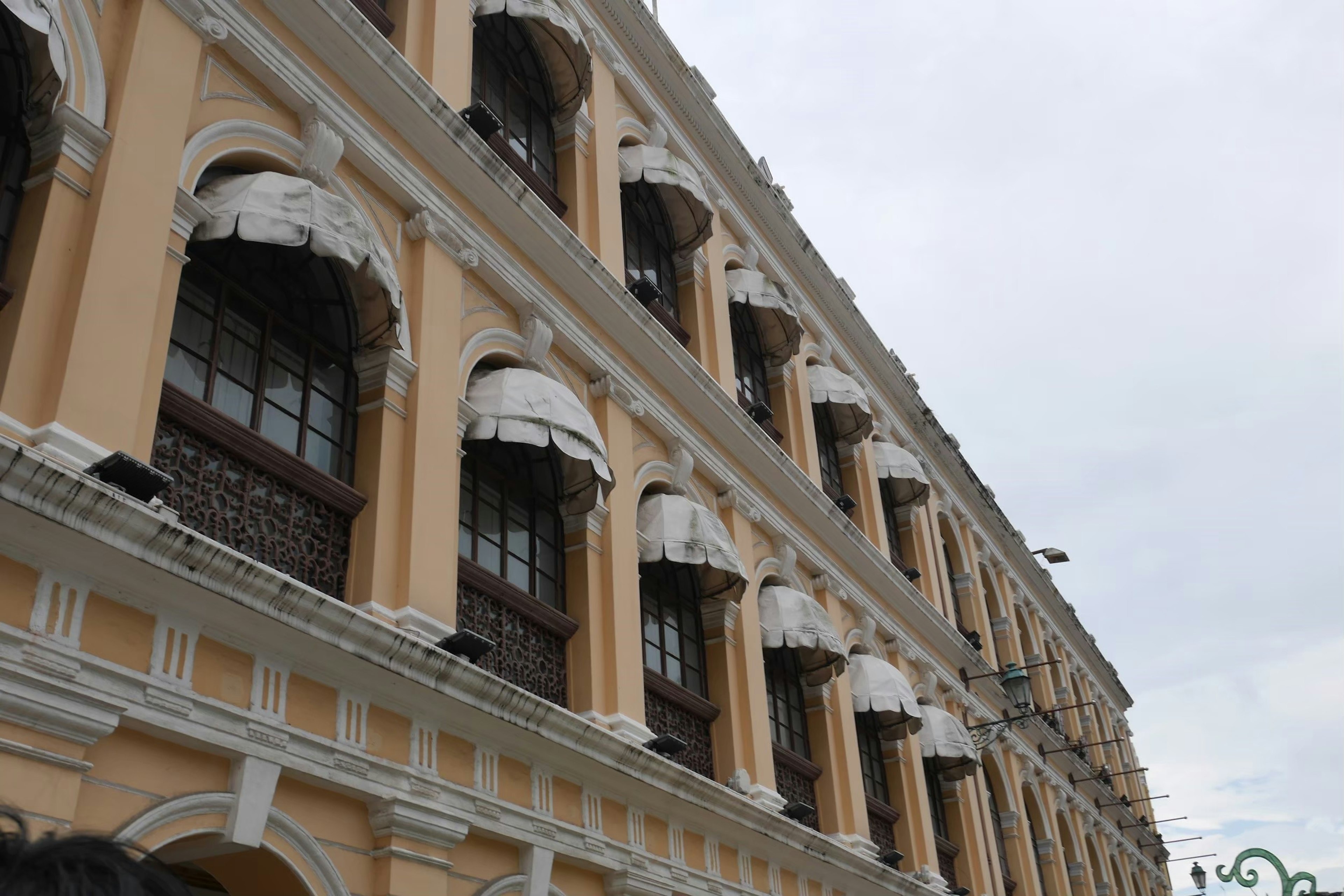 Side view of a building with yellow exterior and decorative window frames