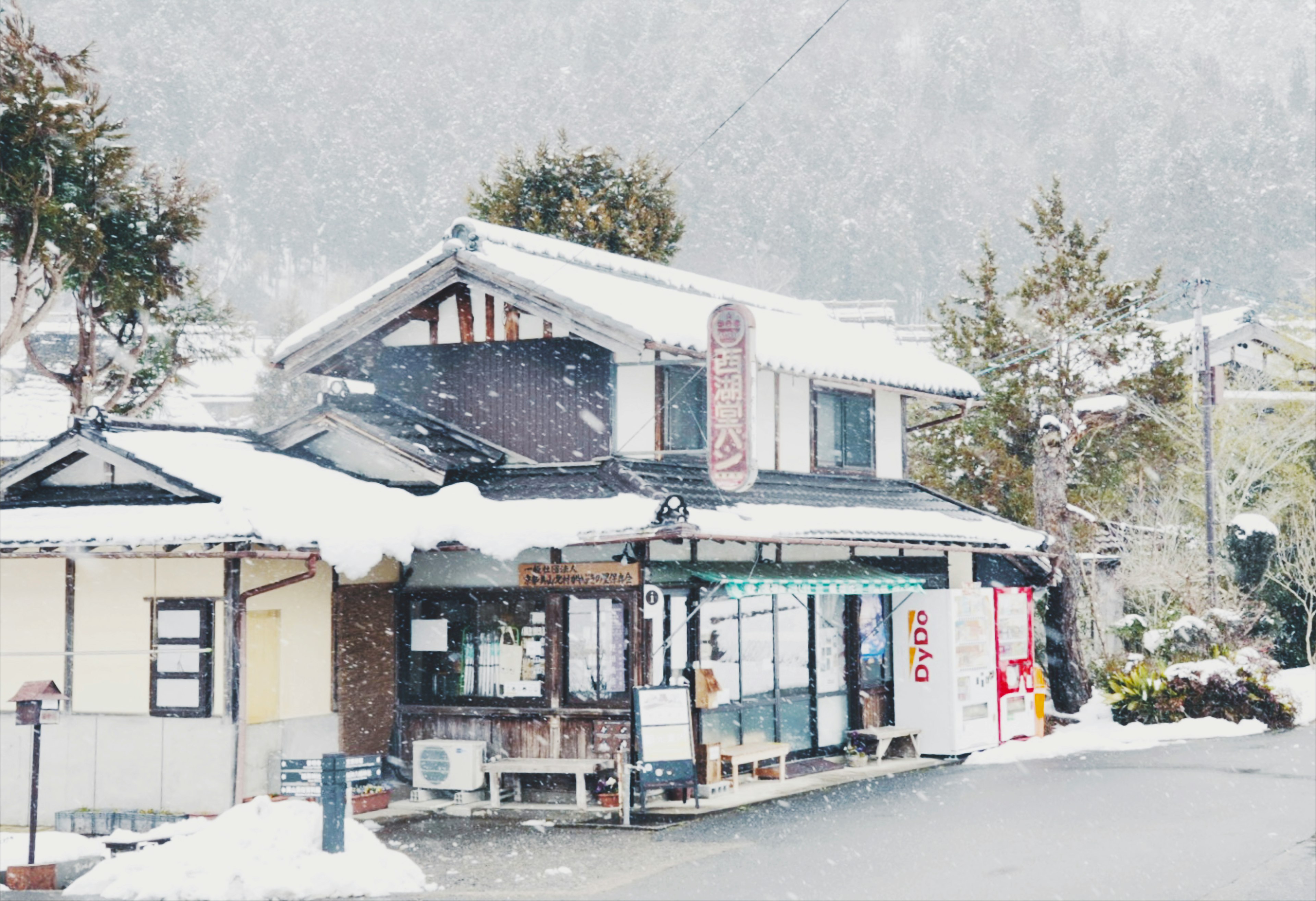 雪に覆われた伝統的な日本の家と店舗が並ぶ風景