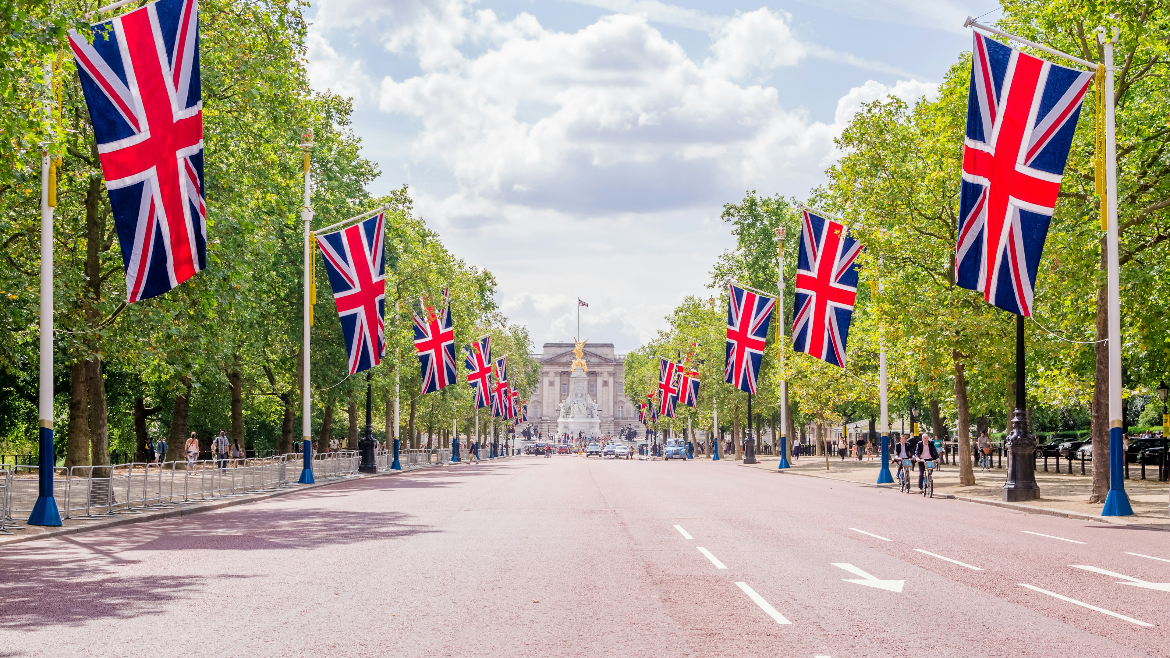 Pathway lined with British flags leading to Buckingham Palace and green trees