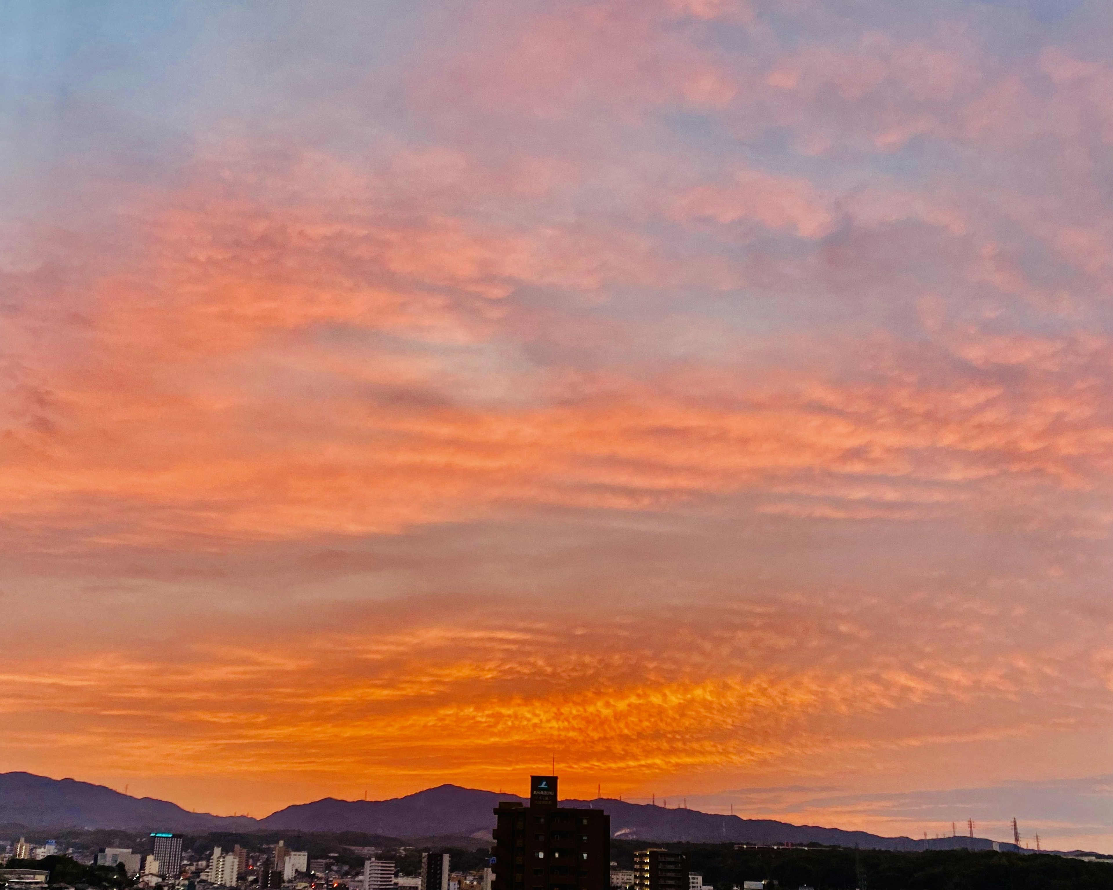 Wunderschöner Sonnenuntergangshimmel mit lebhaften orange und rosa Tönen und Bergsilhouetten