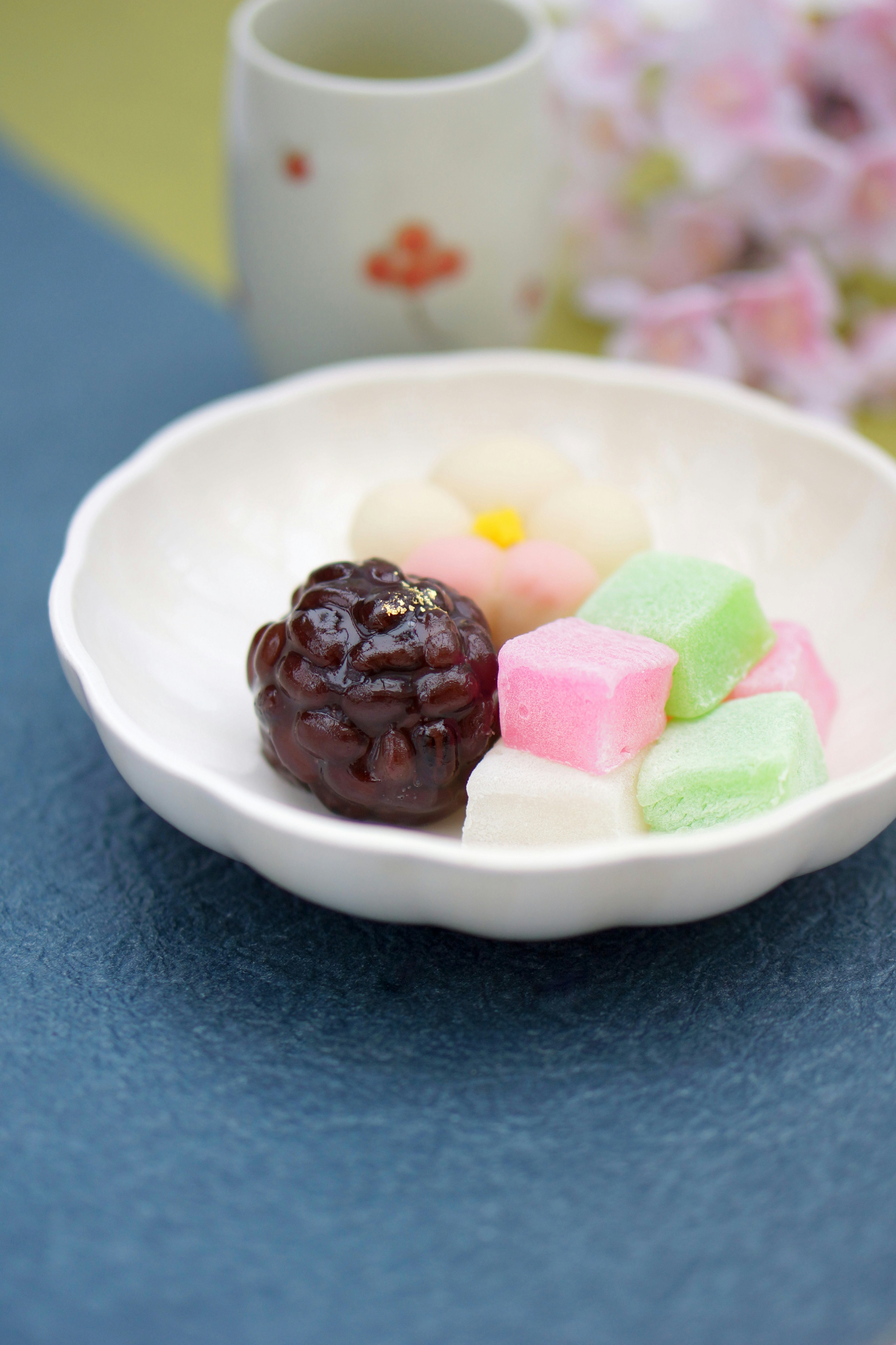 Eine schöne Anordnung von Wagashi auf einem kleinen Teller mit bunten Süßigkeiten und einer schwarzen Süßigkeit