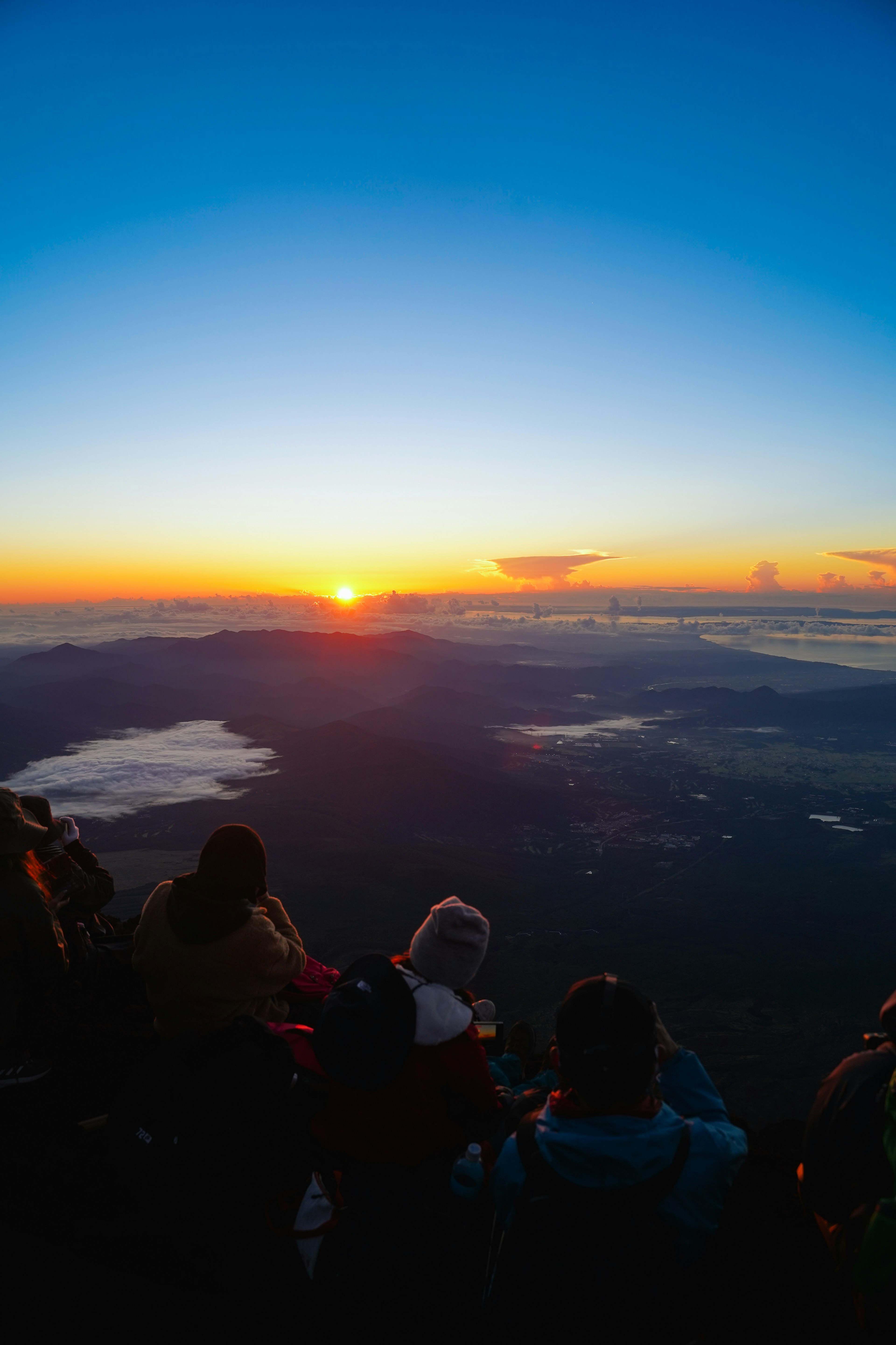 Tourists watching a vibrant sunrise over a mountainous landscape