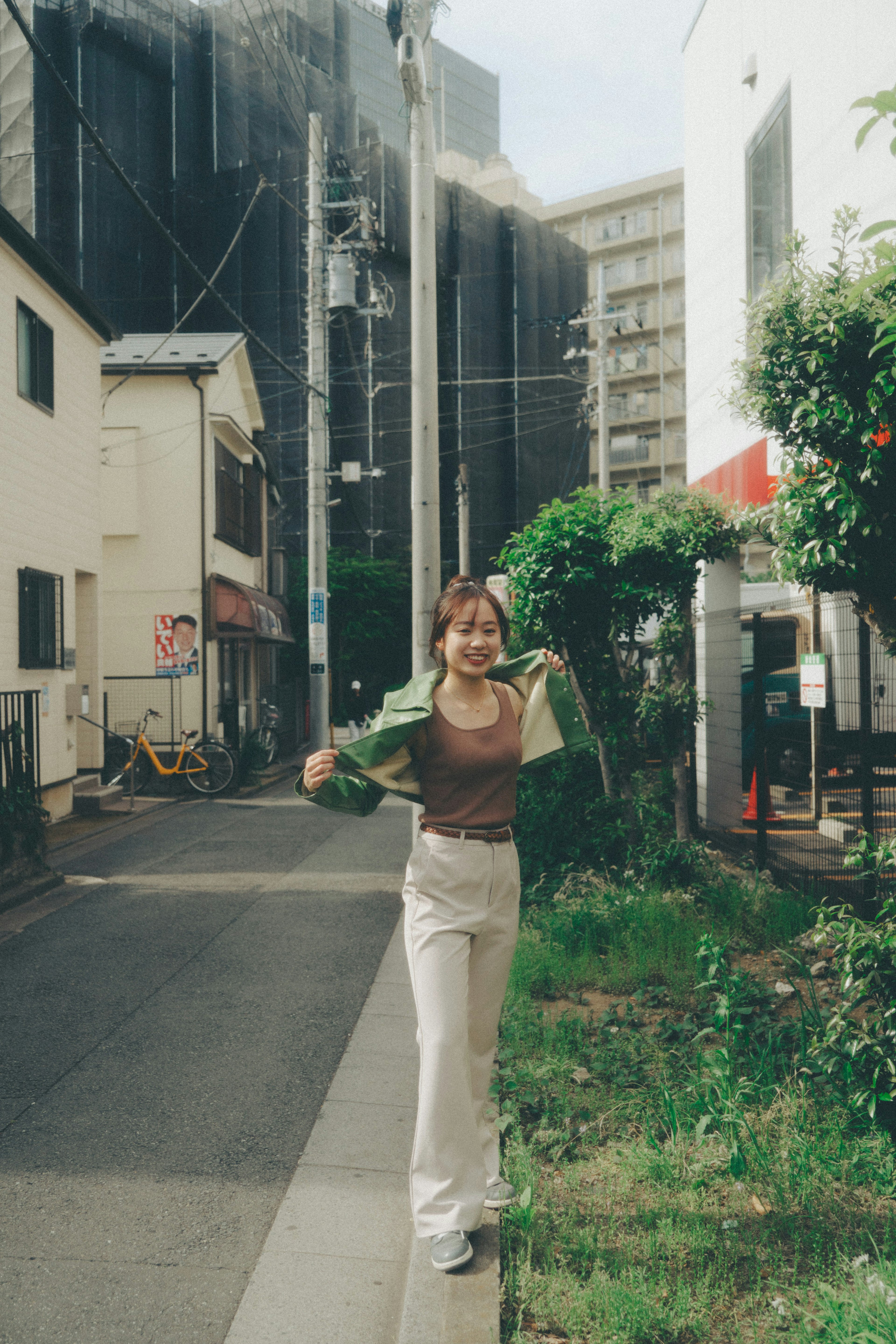 女性が緑のジャケットを着ている街路の風景