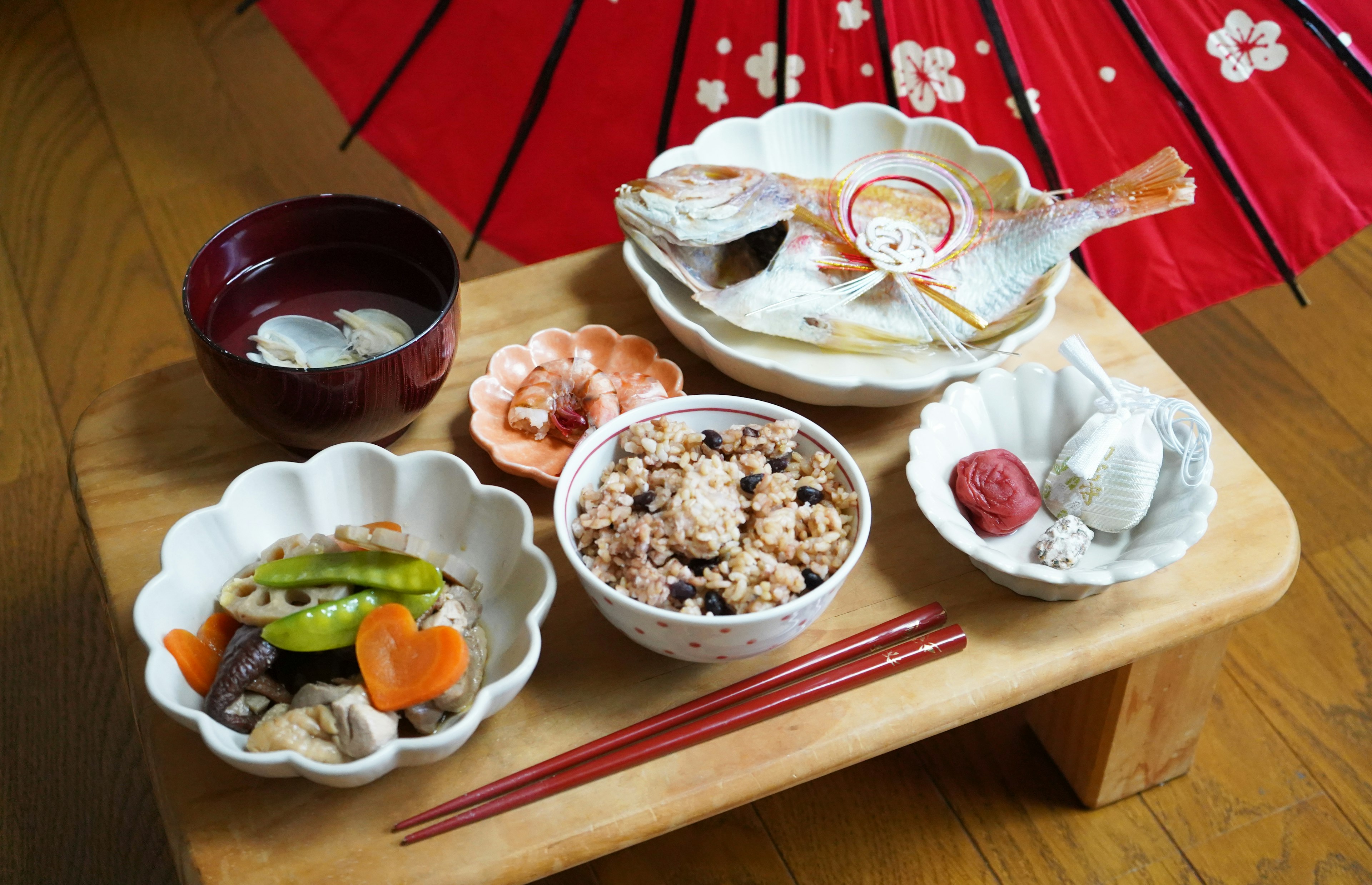 Disposición de una comida japonesa tradicional bajo un paraguas rojo