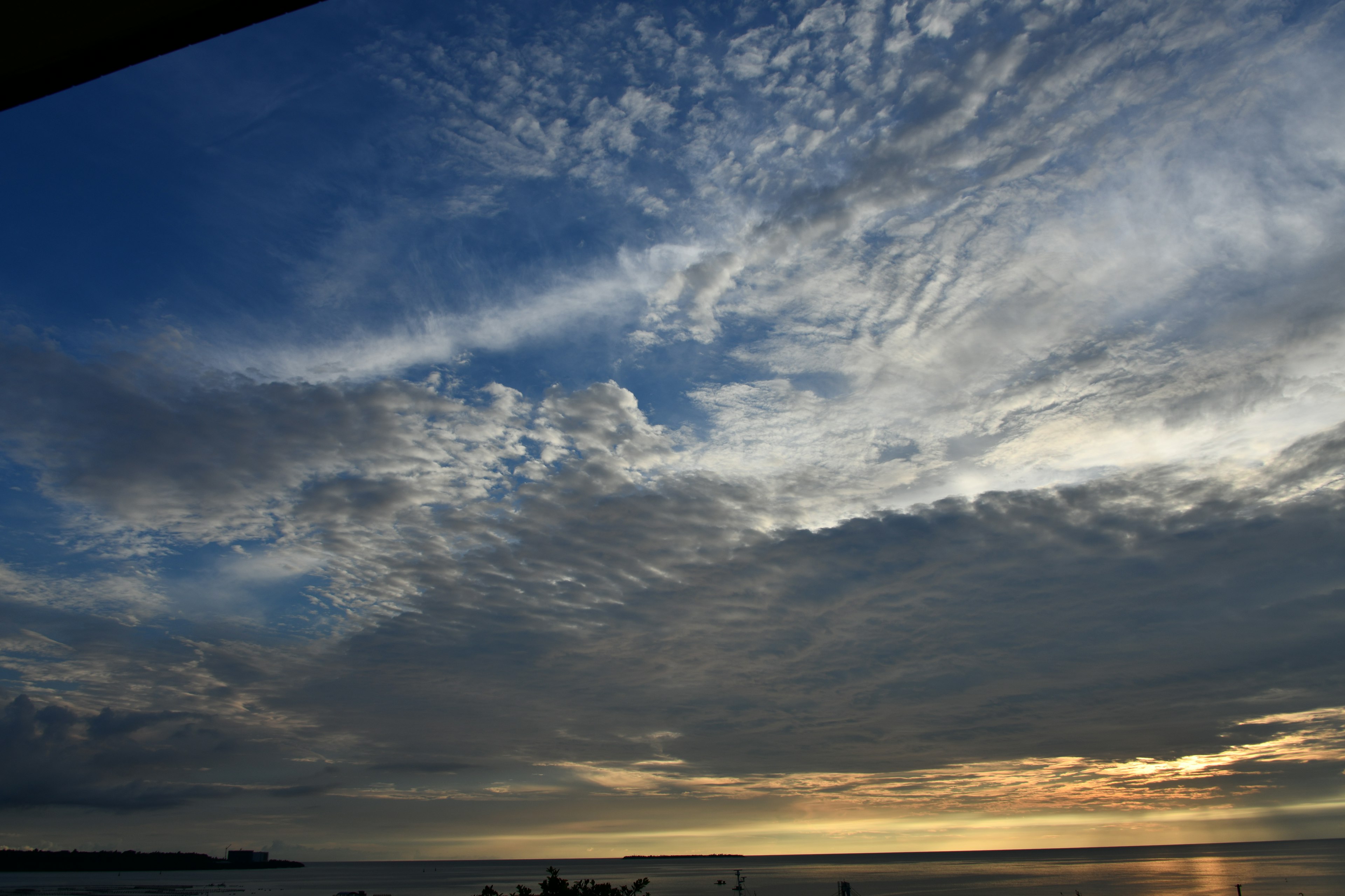 Langit biru yang indah dengan awan tersebar dan matahari terbenam di atas laut