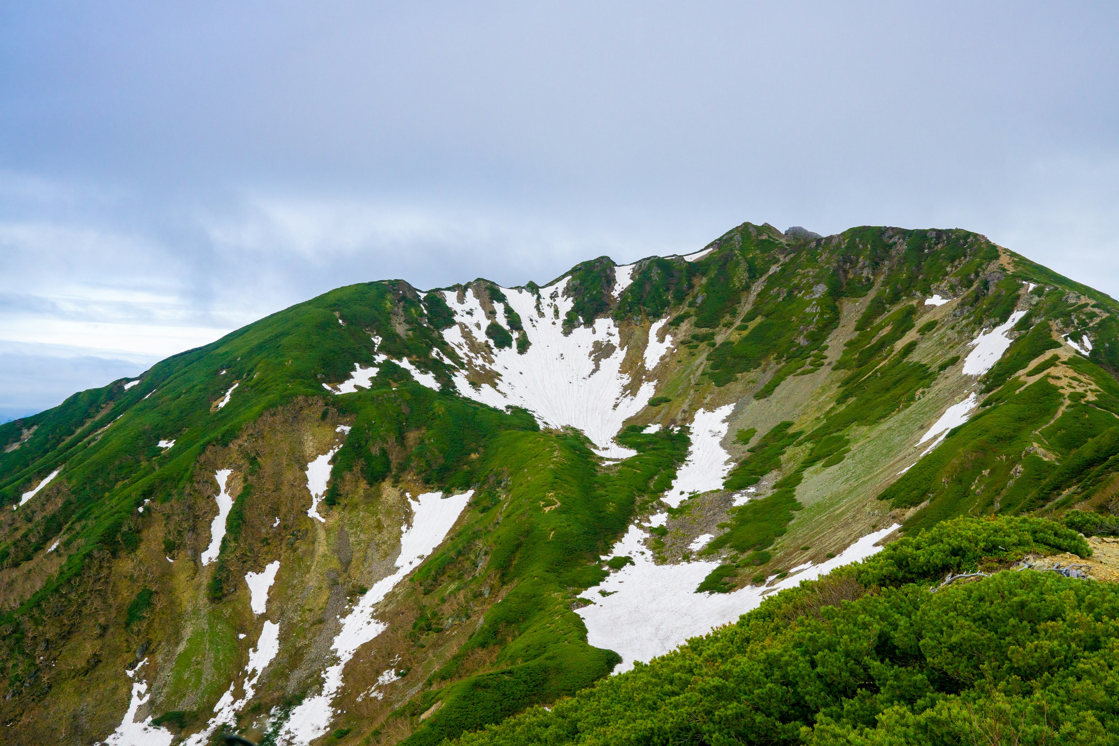 Scenic mountain landscape with green slopes and patches of snow