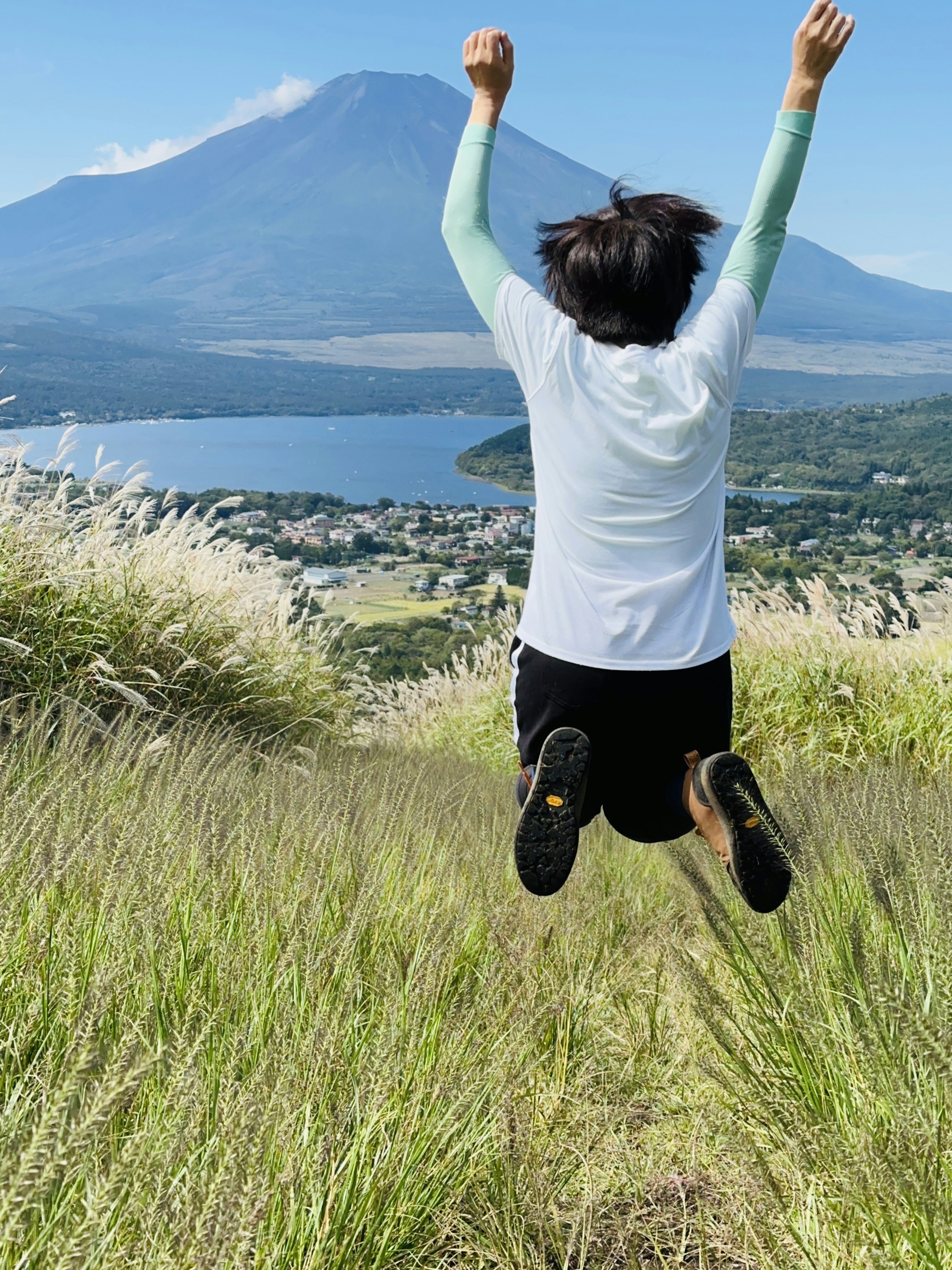 Kind springt mit erhobenen Armen vor einer Berglandschaft