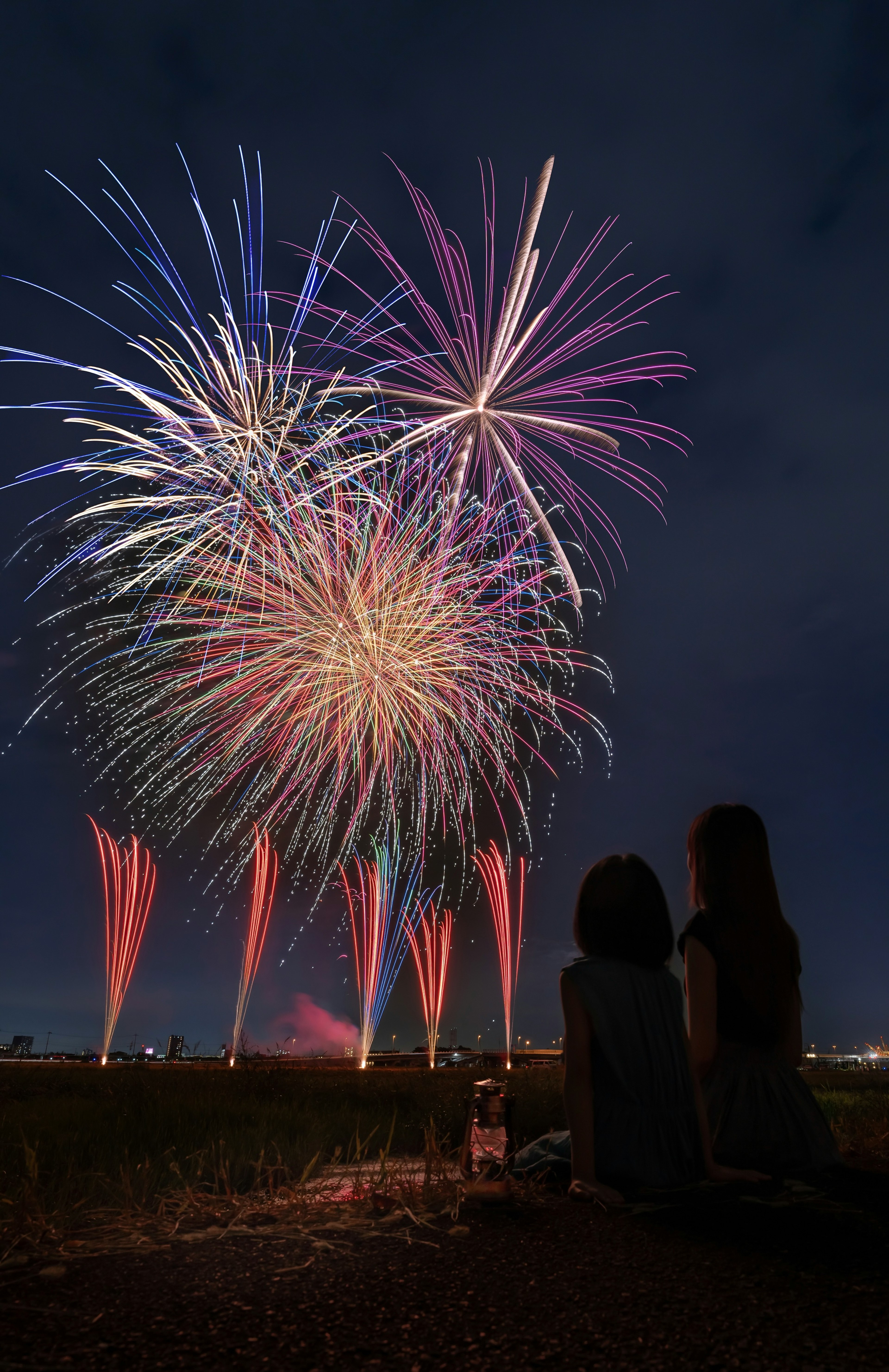 夜空に打ち上げられた花火とそれを見つめる二人の人影