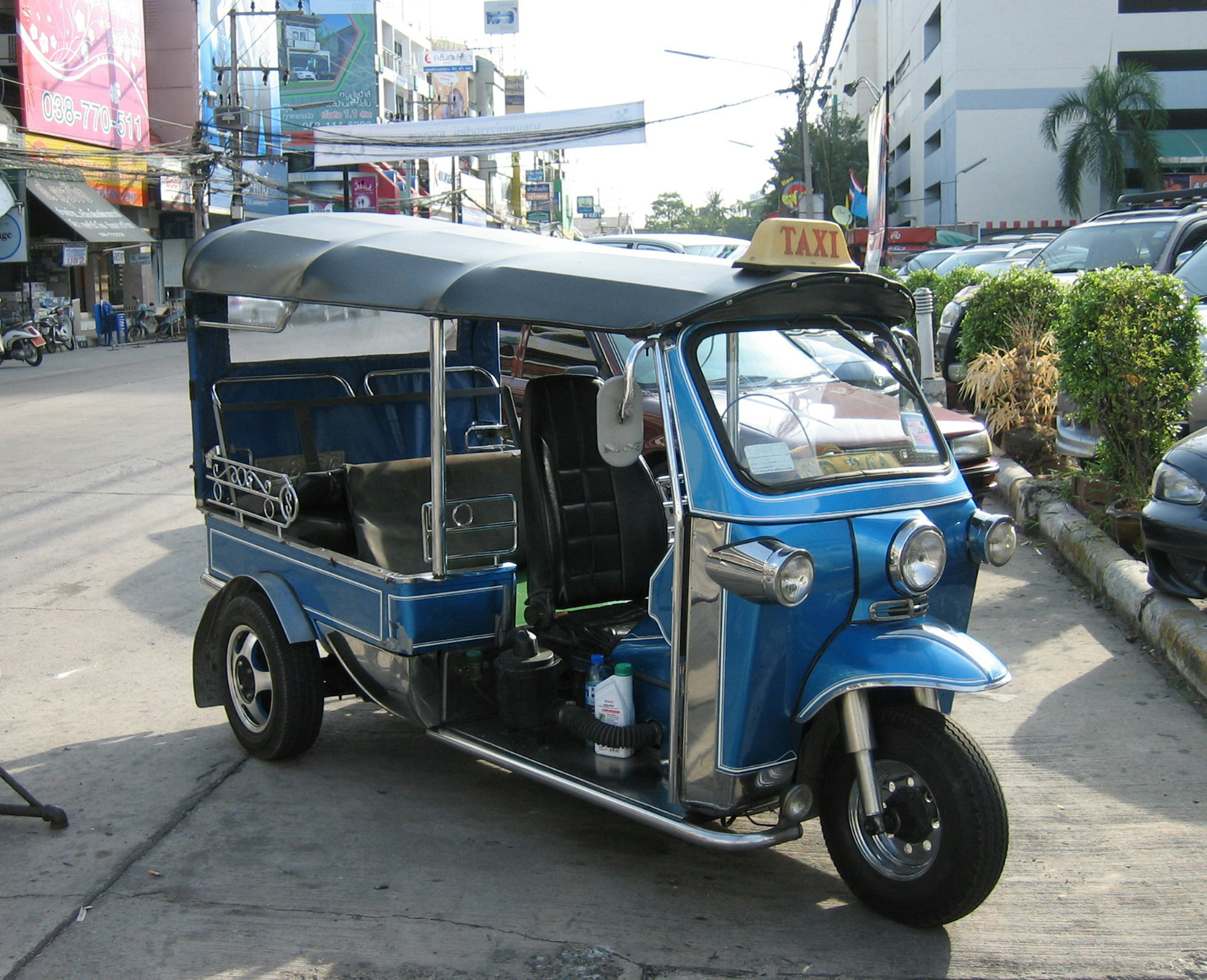 Blue tuk-tuk parked on a street with buildings in the background