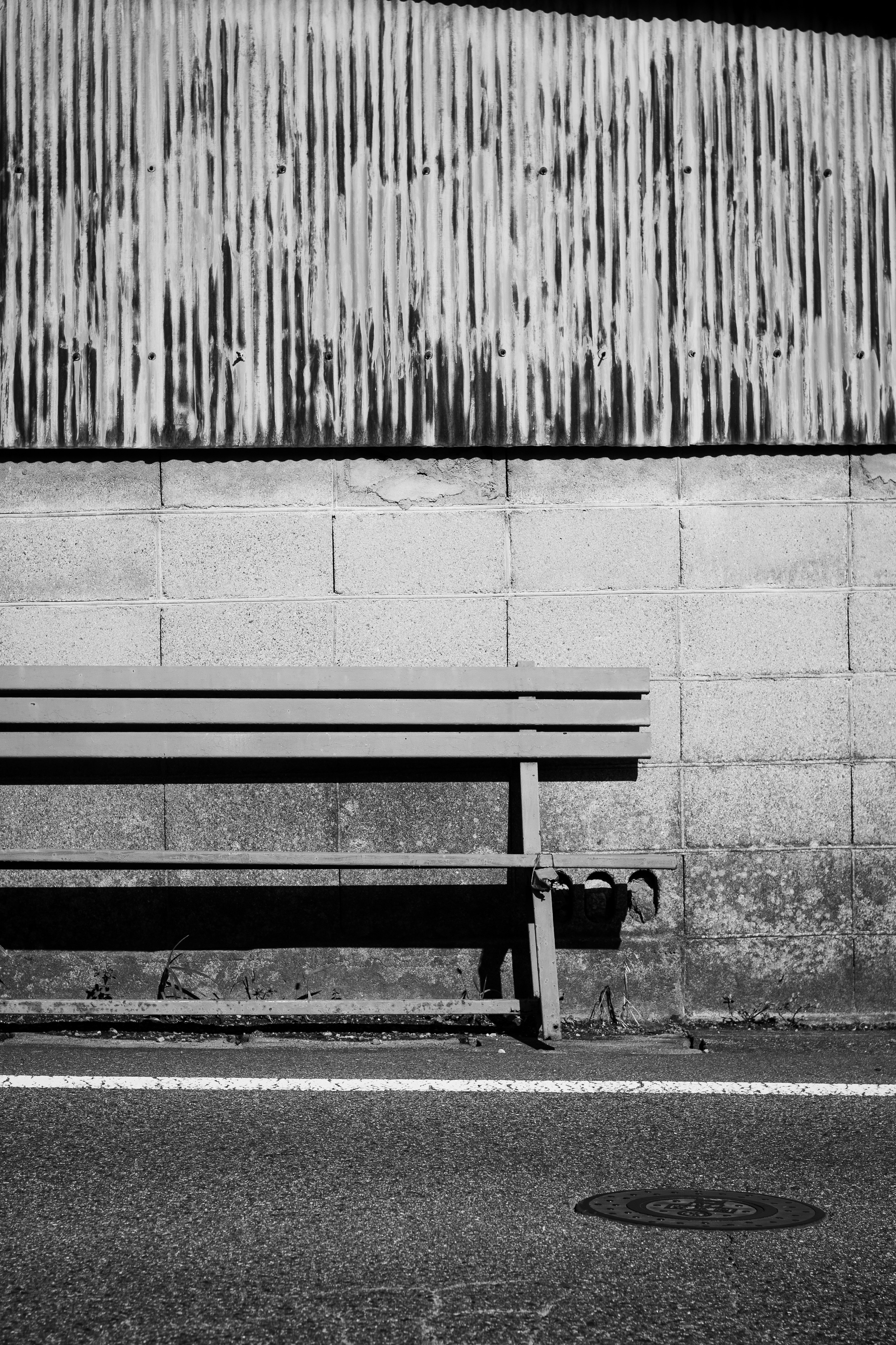 Photo en noir et blanc d'un banc contre un mur texturé