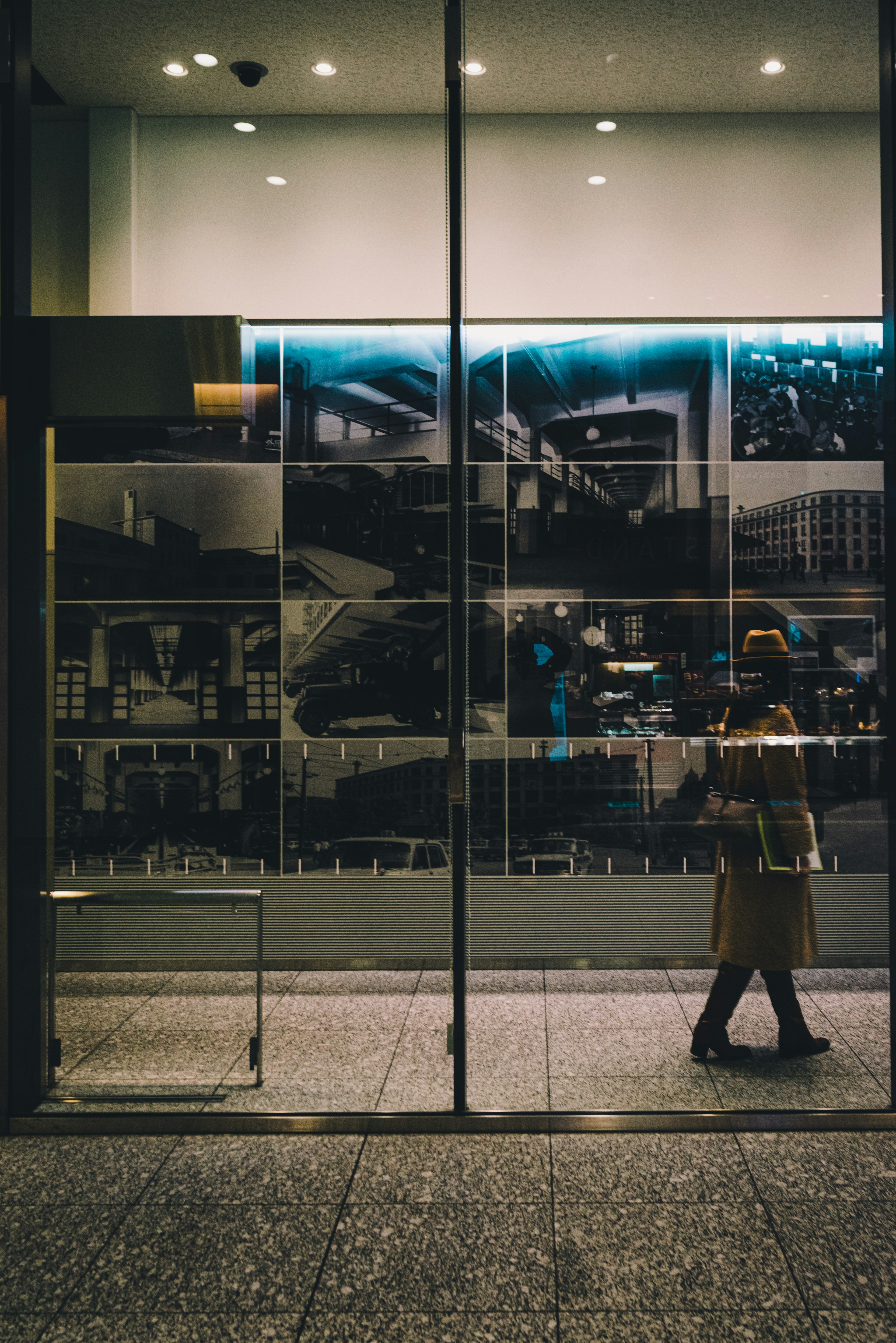 Person standing in front of glass storefront with monochrome photo collage in background