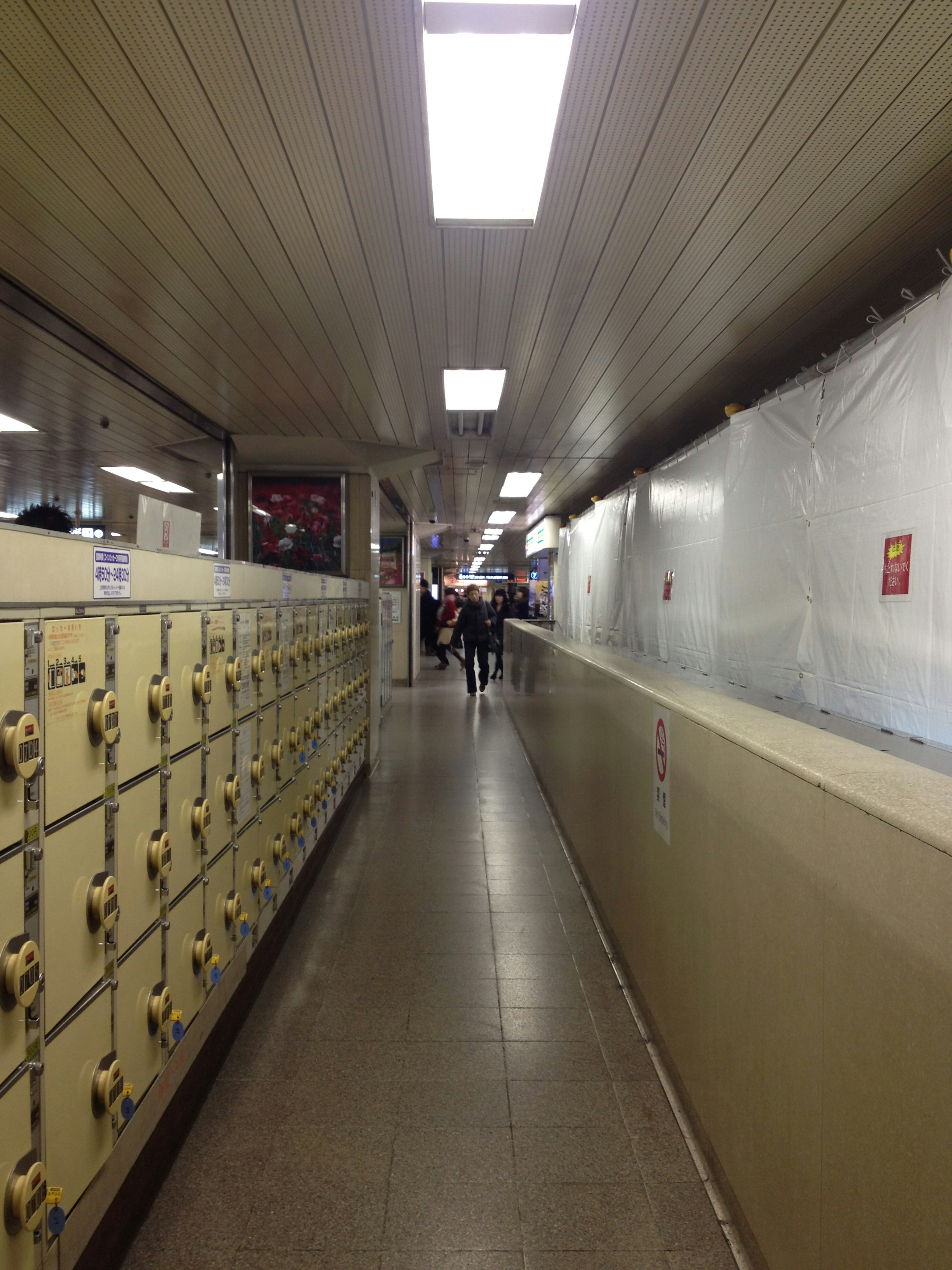 Long corridor with lockers and bright overhead lights