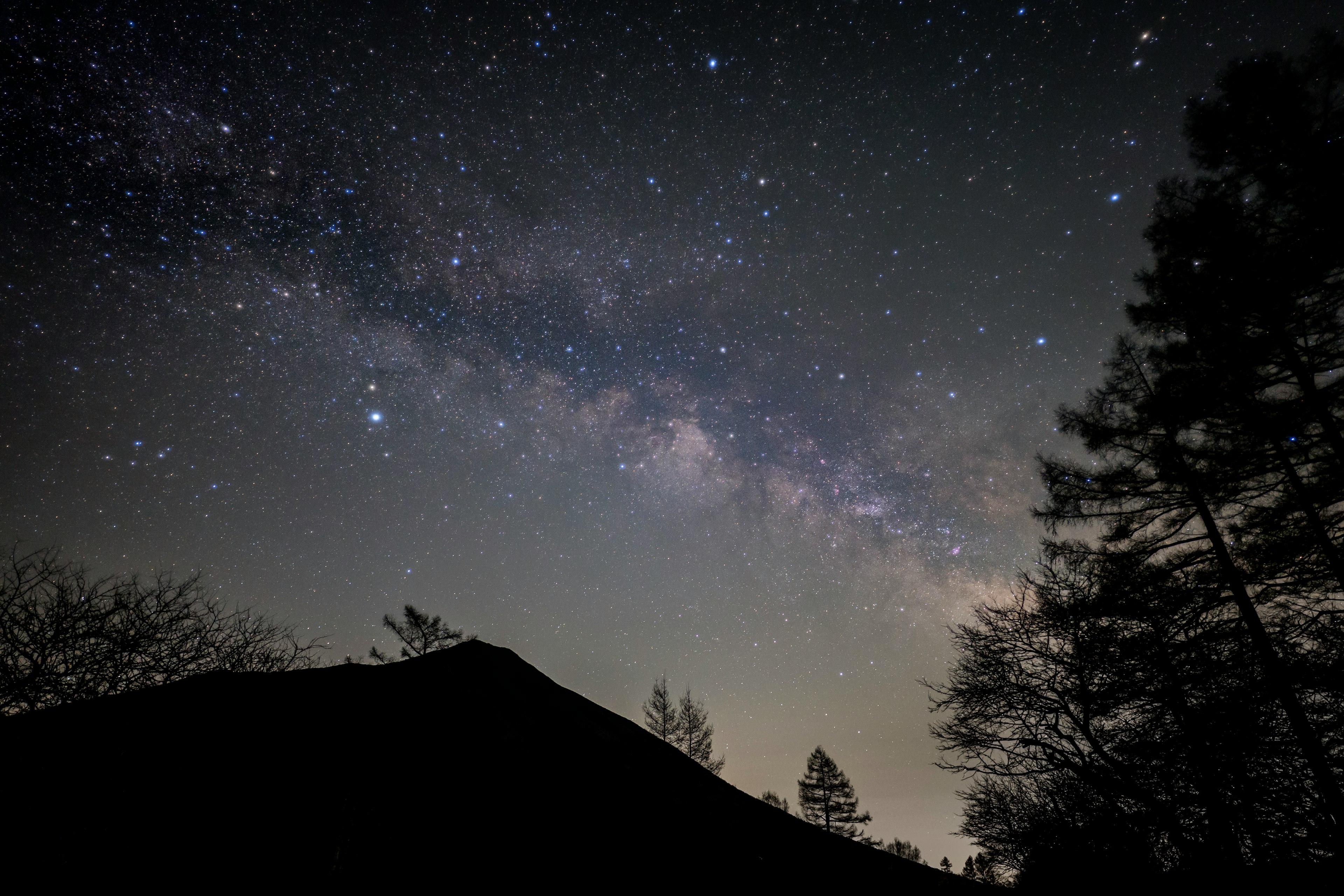 星空の下に広がる天の川と山のシルエット