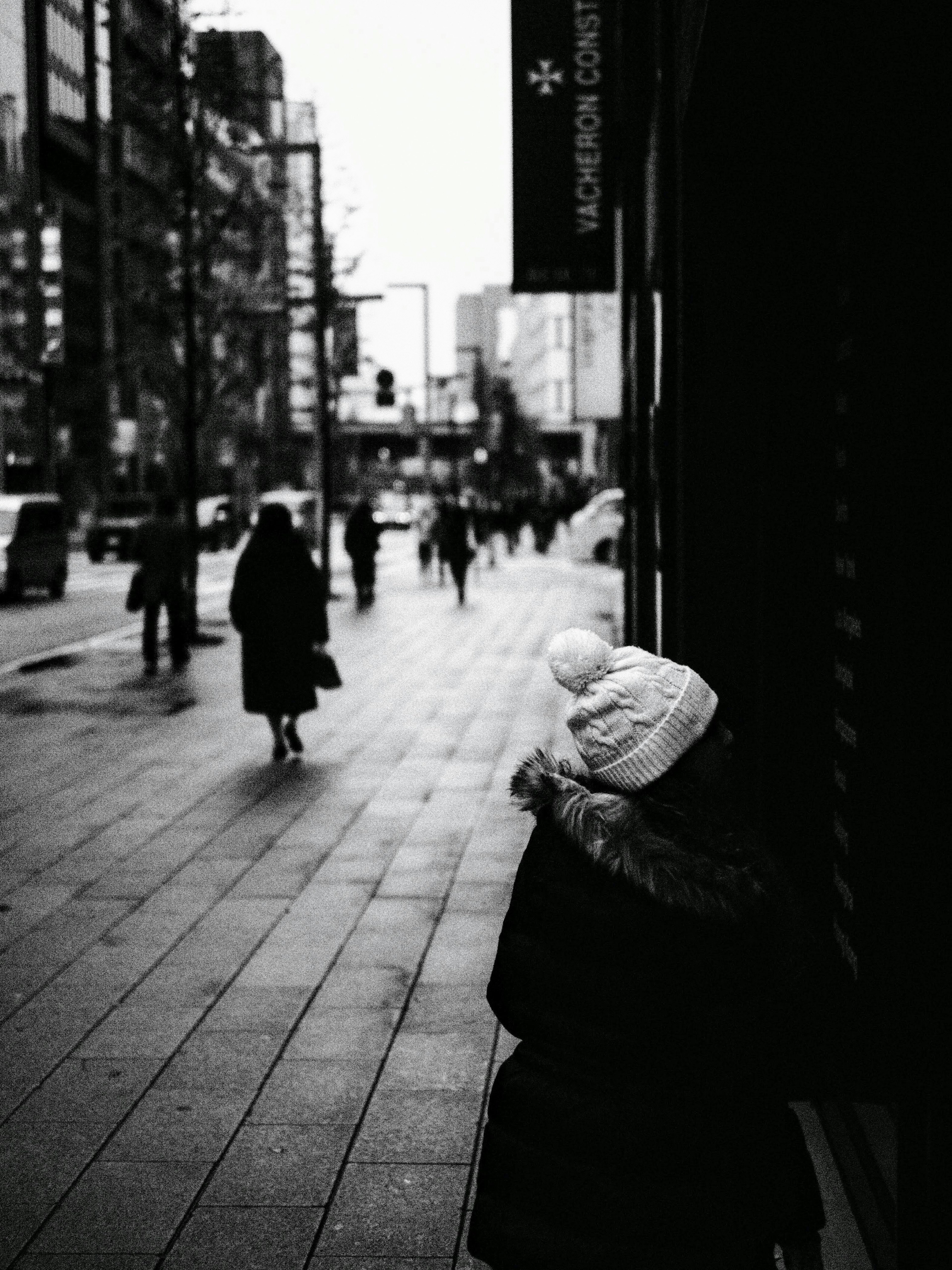 Bambino con un cappello bianco su una strada di città con pedoni in silhouette