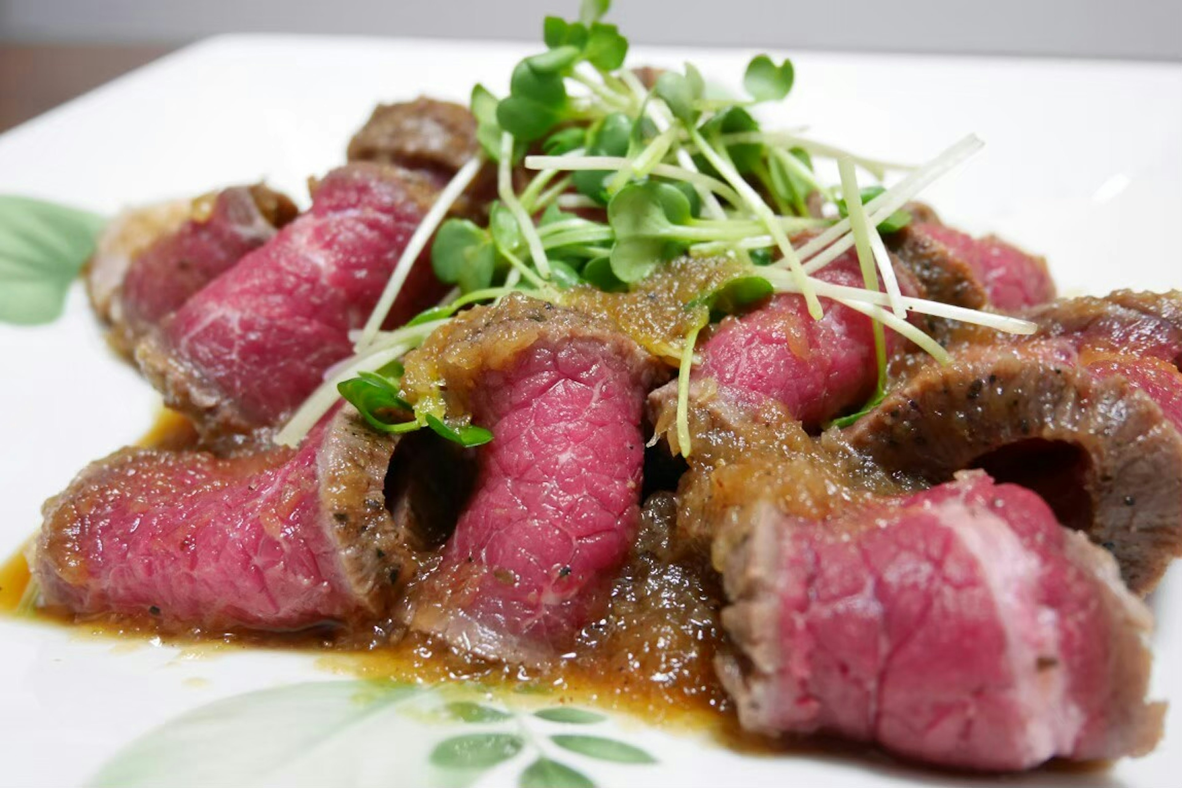 Carne asada en rodajas decorada con hierbas y salsa